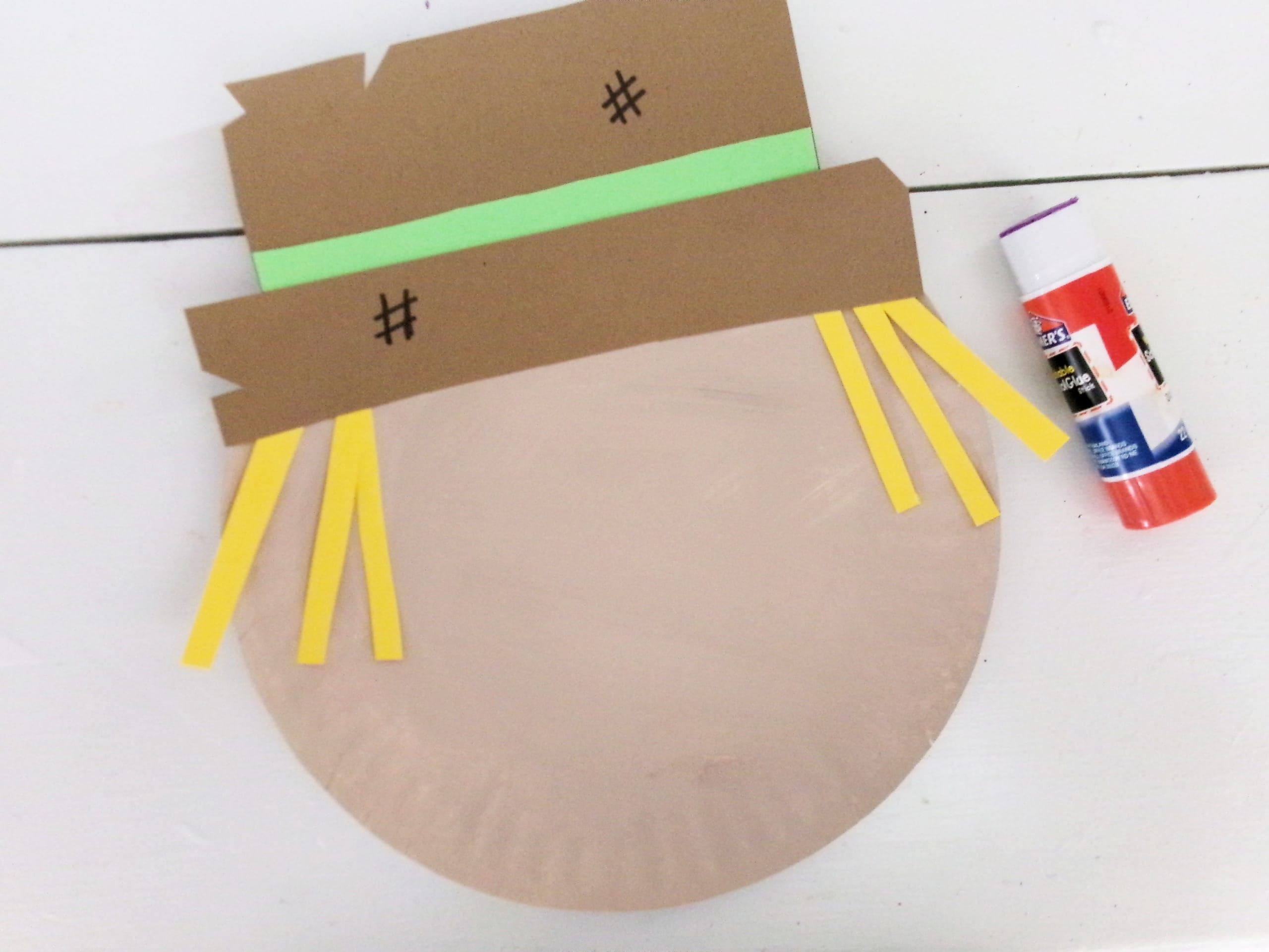 Glue the hat with Hair onto the top of the tan paper plate.