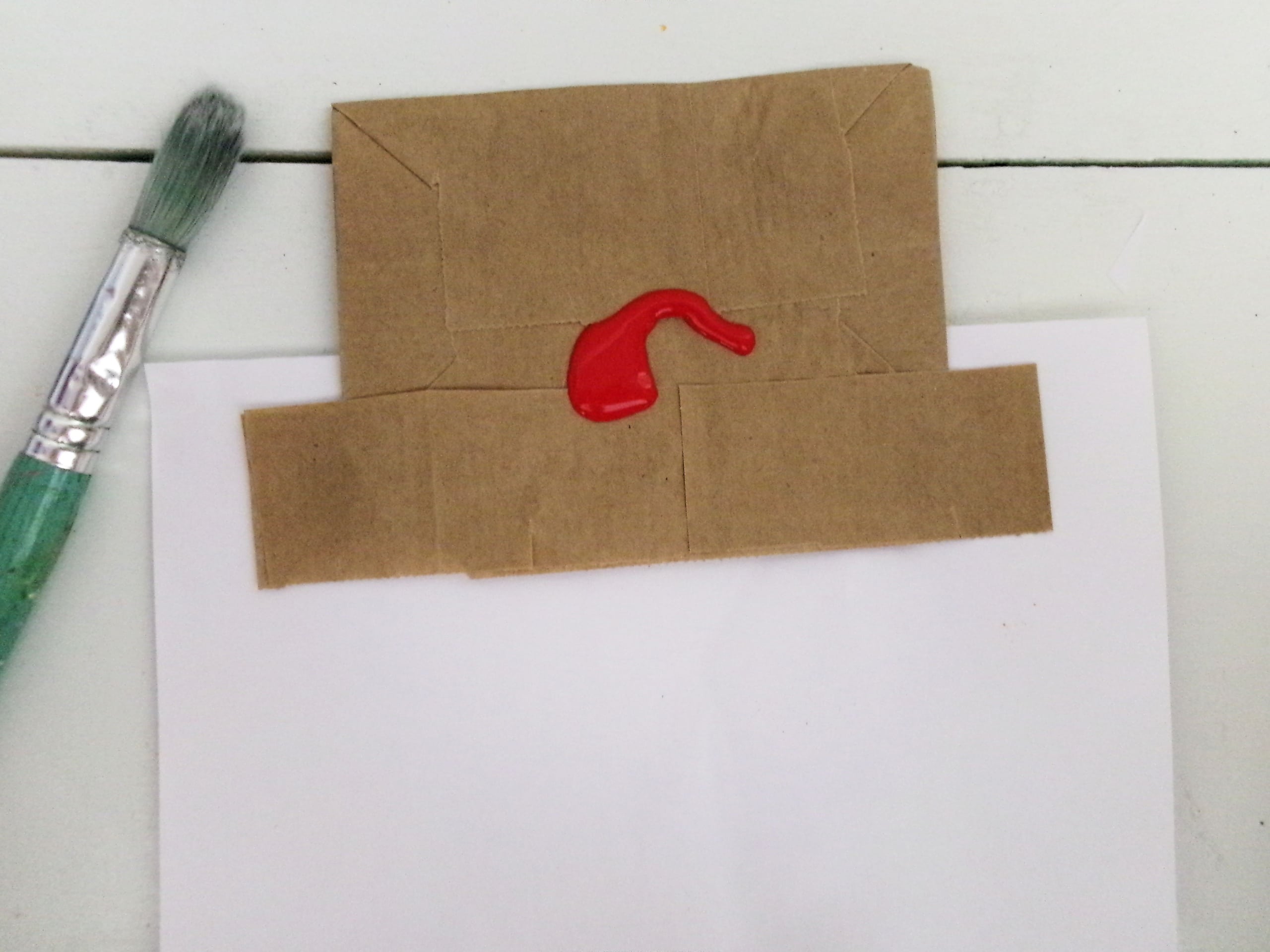 Put a scrap piece of paper under the flap of the paper bag and paint the top part the color of your choice.