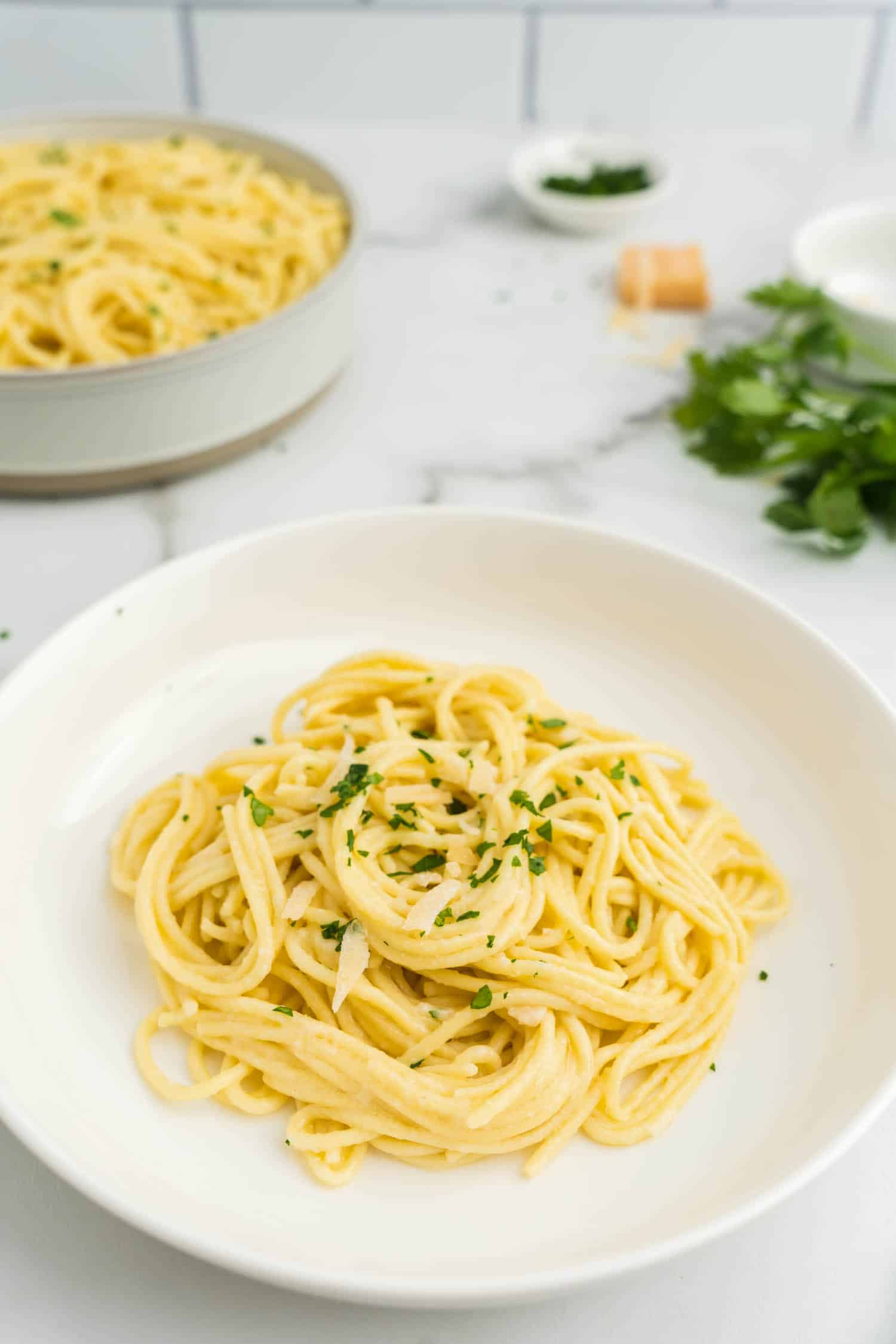 Close up photo of buttered noodles topped with parmesan cheese and parsley