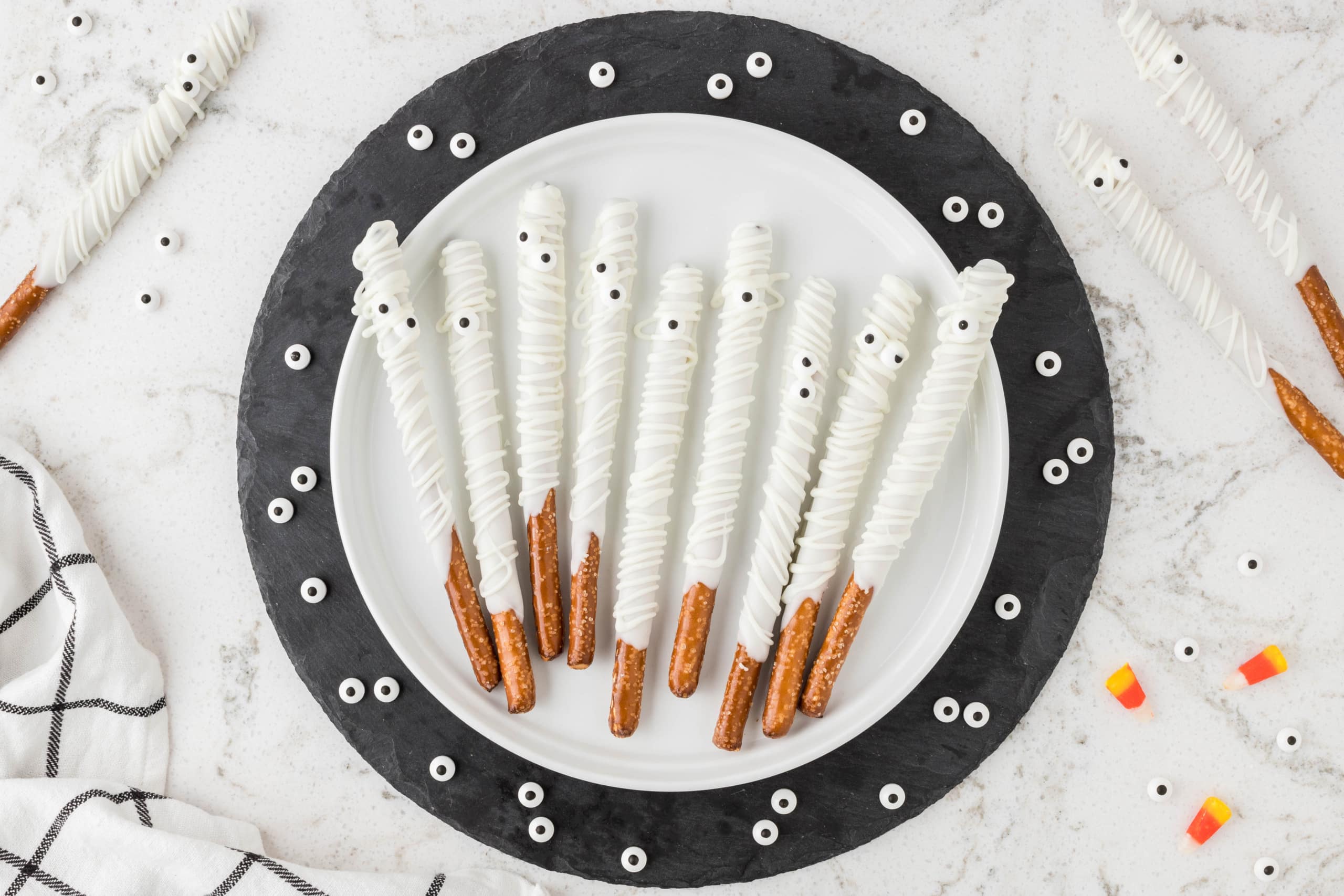 Mummy Pretzel Rods displayed on a white plate with black trim.