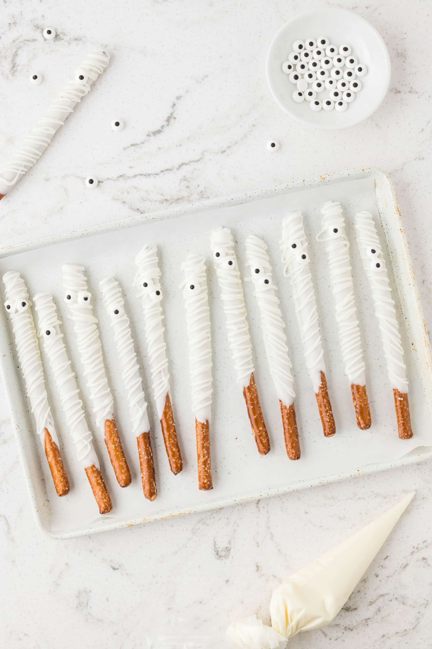 Cut the tip of the piping bag filled with melted almond bark and drizzle back and forth on top of the pretzel rods.