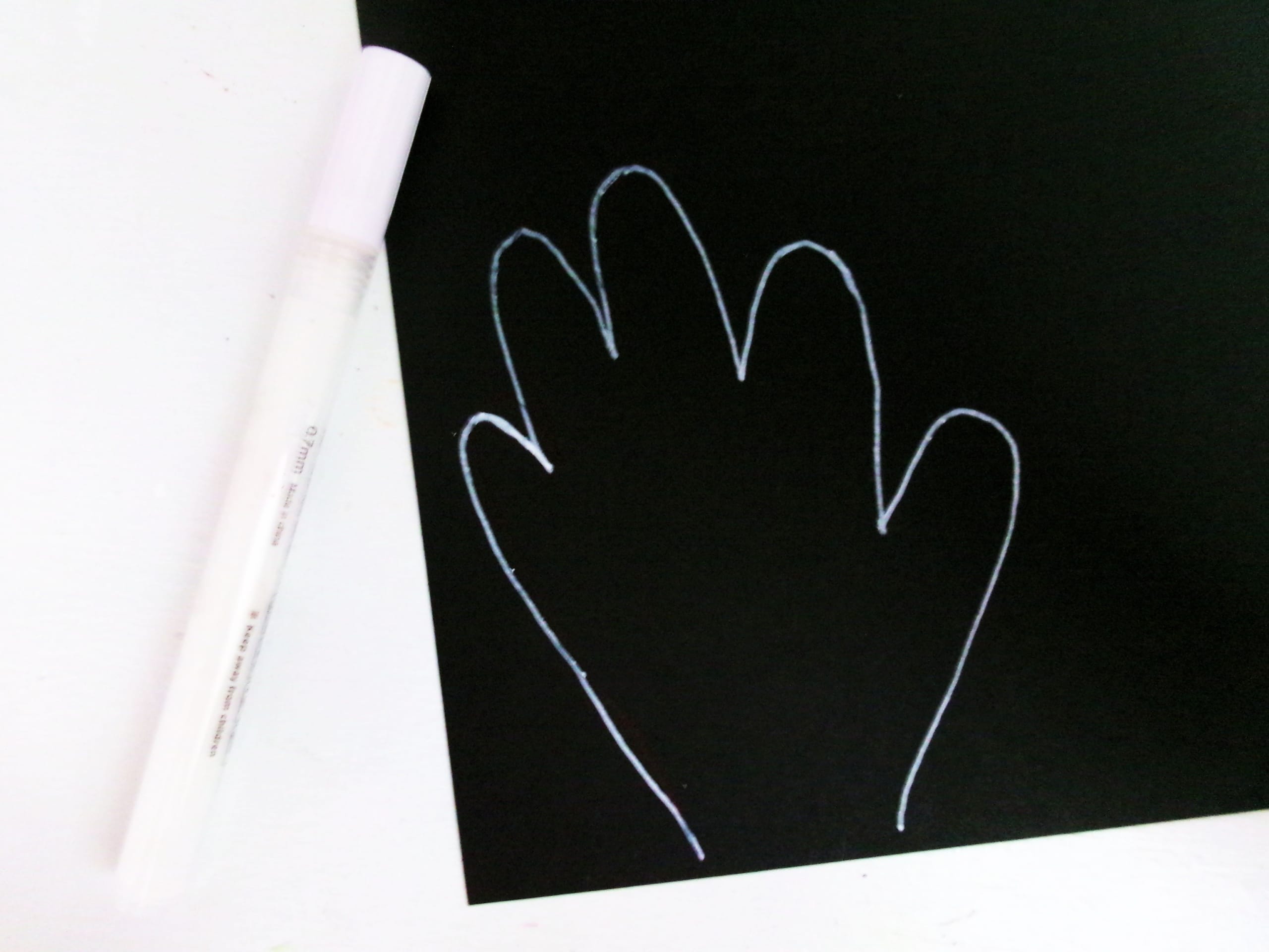 Trace two hands on the black sheet of paper and cut out. Round the wrist part of the hands.