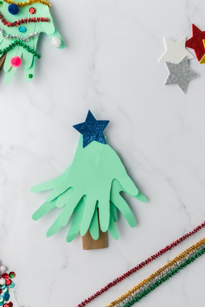 Glue the third handprint on the top to make the top of the christmas tree. add a star at the top of the hands.