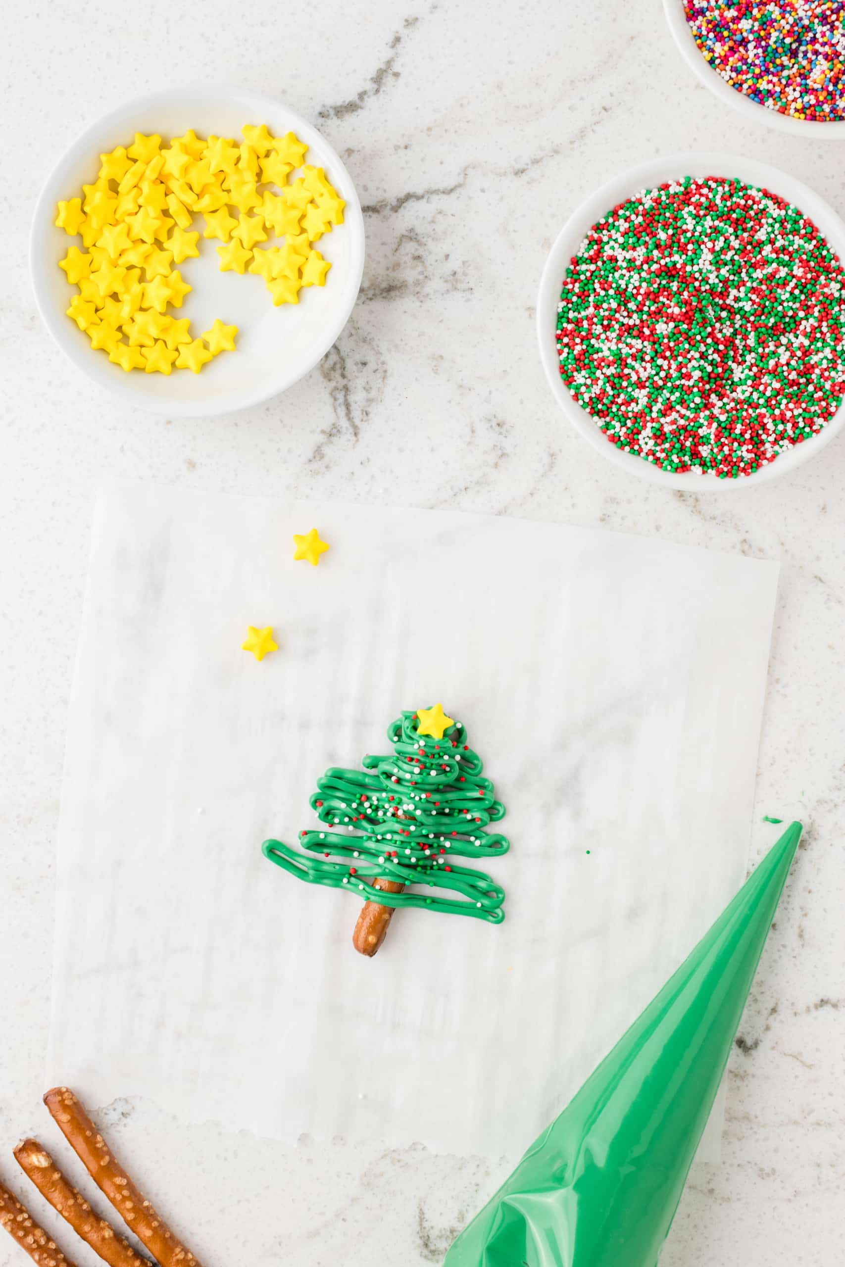 Add sprinkles and a star at the top of the zig zag Christmas tree pretzel
