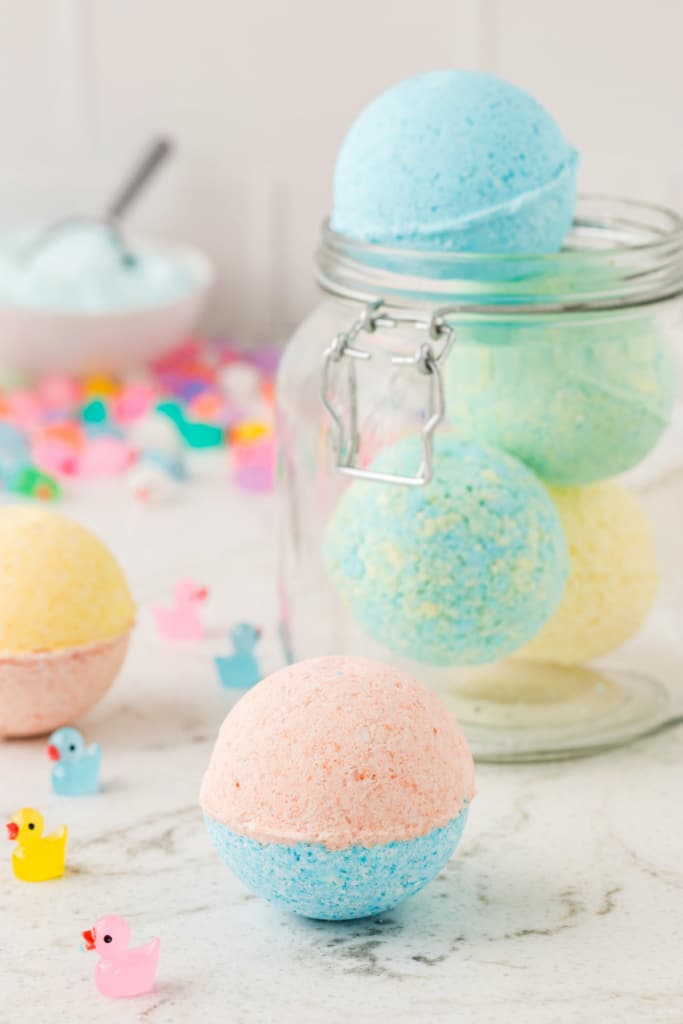 Completed Bath bombs in a mason jar with one sitting out on the table in front of the mason jar.