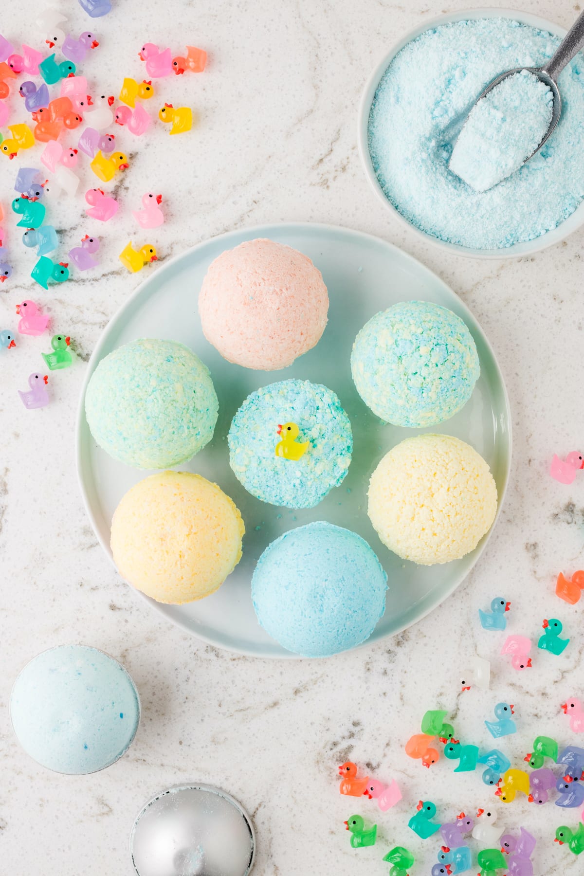 Completed Bath Bombs displayed on a plate with trinkets/toys all around on the table.