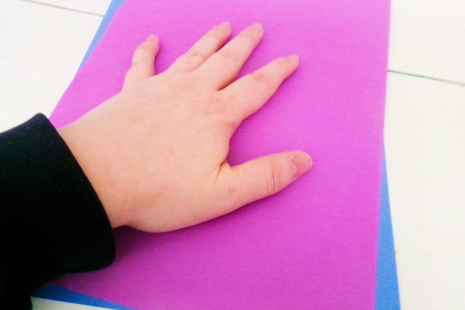 Hand pressing paint into paper with another paper