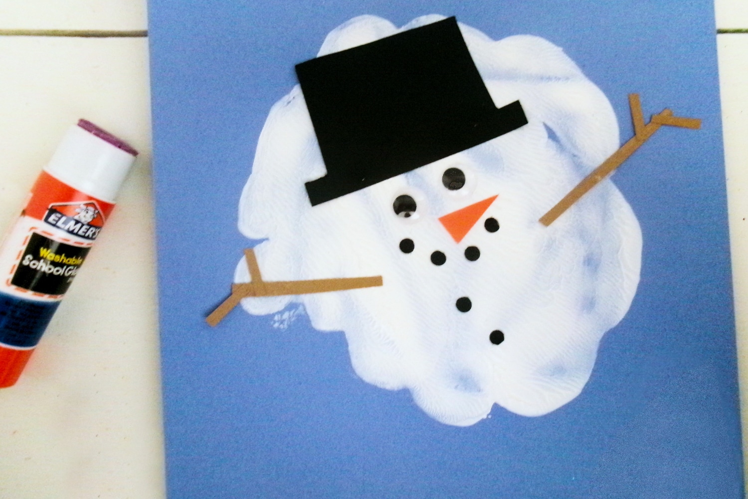 White paint splat with snowman hat, eyes, mouth, buttons and arms