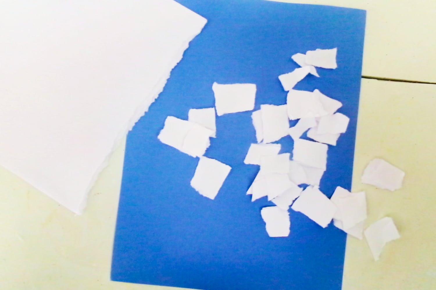 Pieces of ripped white paper on blue cardstock