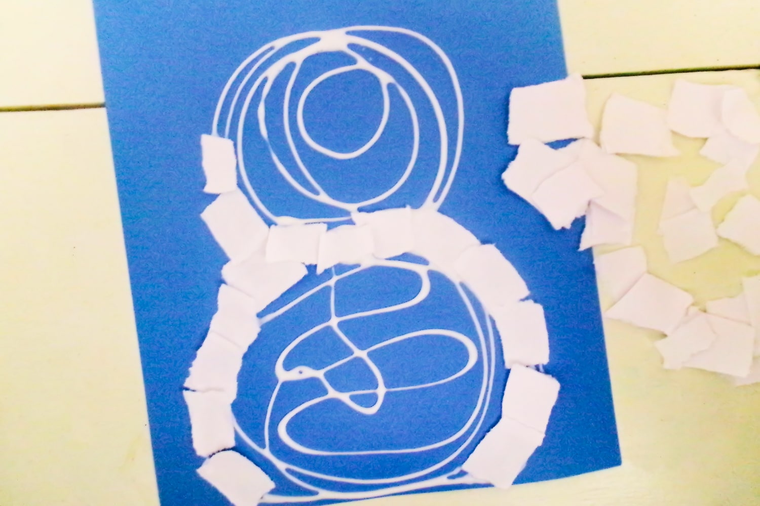 Glue on blue paper in shape of snowman with ripped white paper