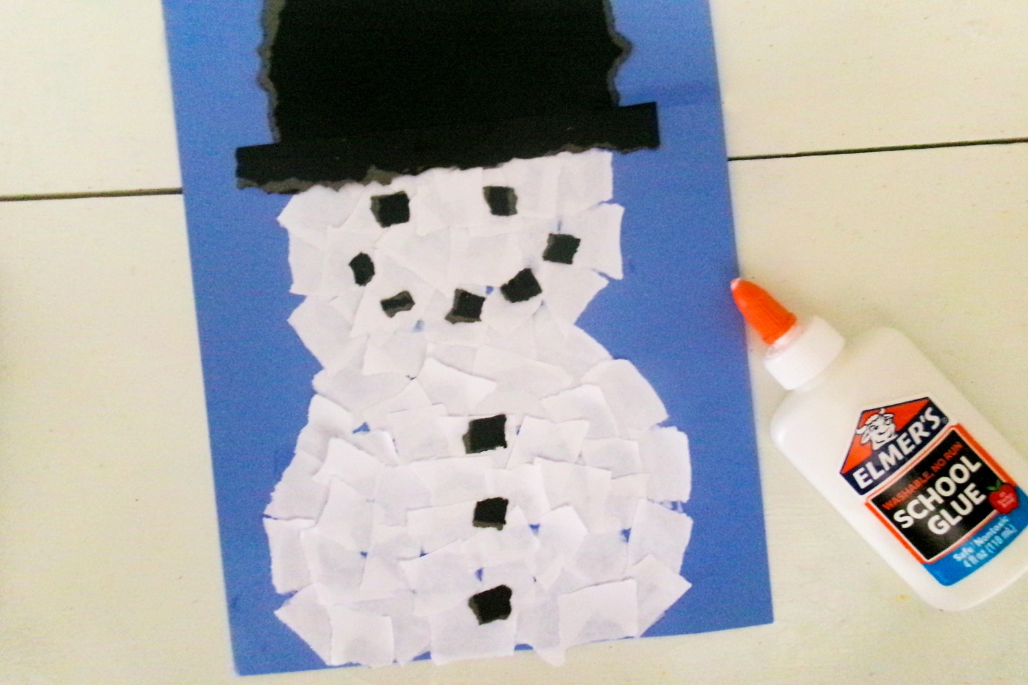 Ripped paper snowman with eyes and hat and buttons