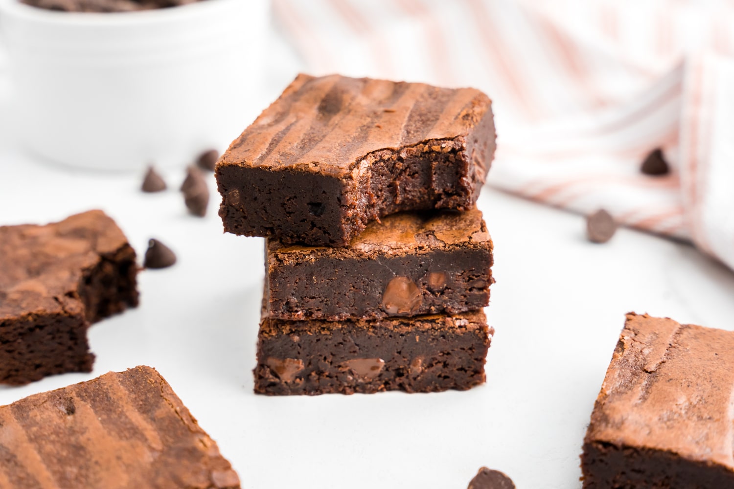 Homemade Brownies cut into squares stacked on plate with one bite taken