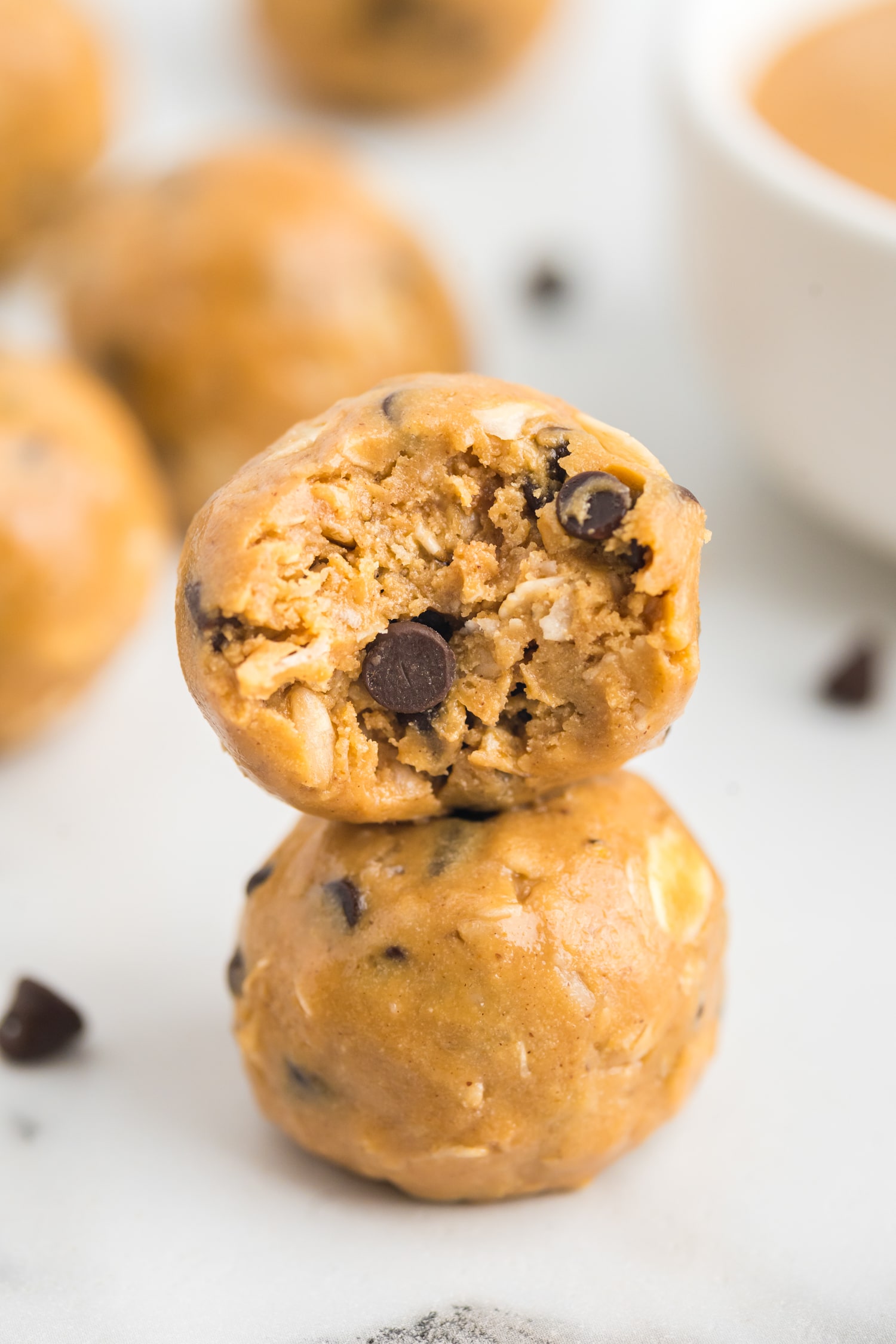 two energy balls stacked on top of one another, with a bite taken out of the top one.