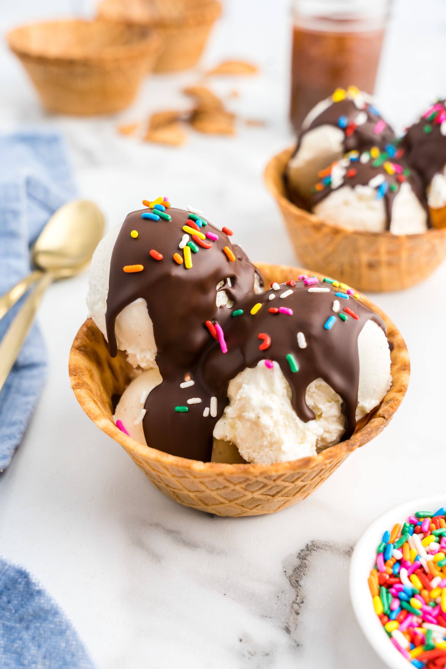 Homemade Magic Shell topped with sprinkles over vanilla ice cream in waffle cone sundae bowl