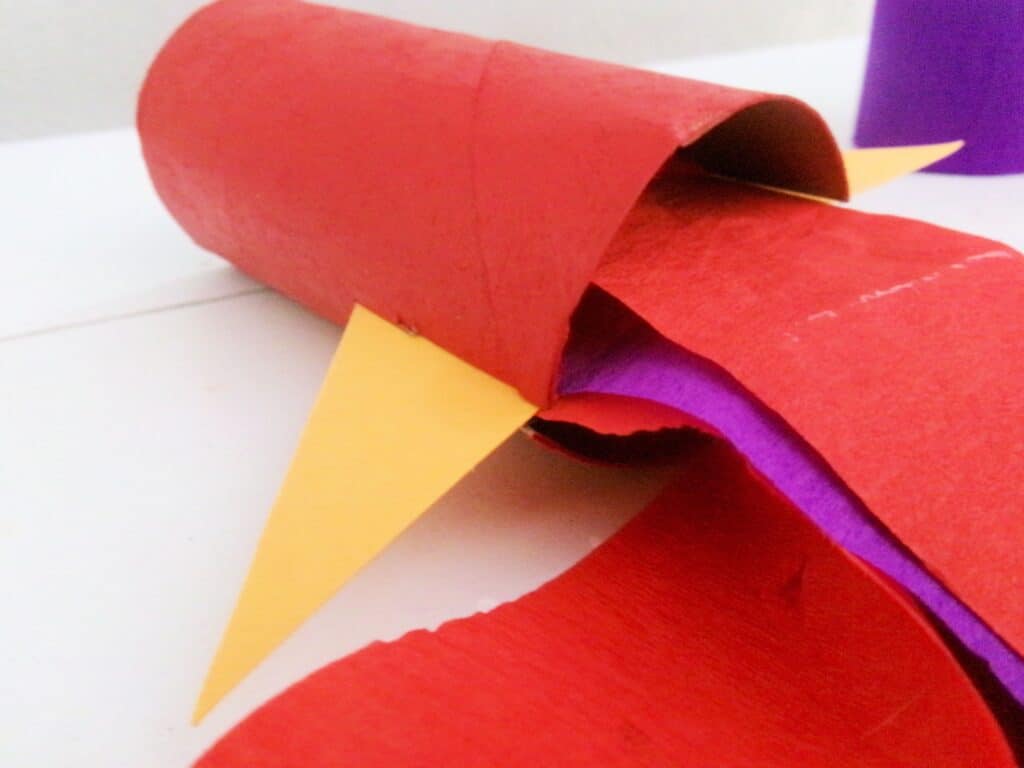 Insert the triangle in the slits of the toilet paper roll.