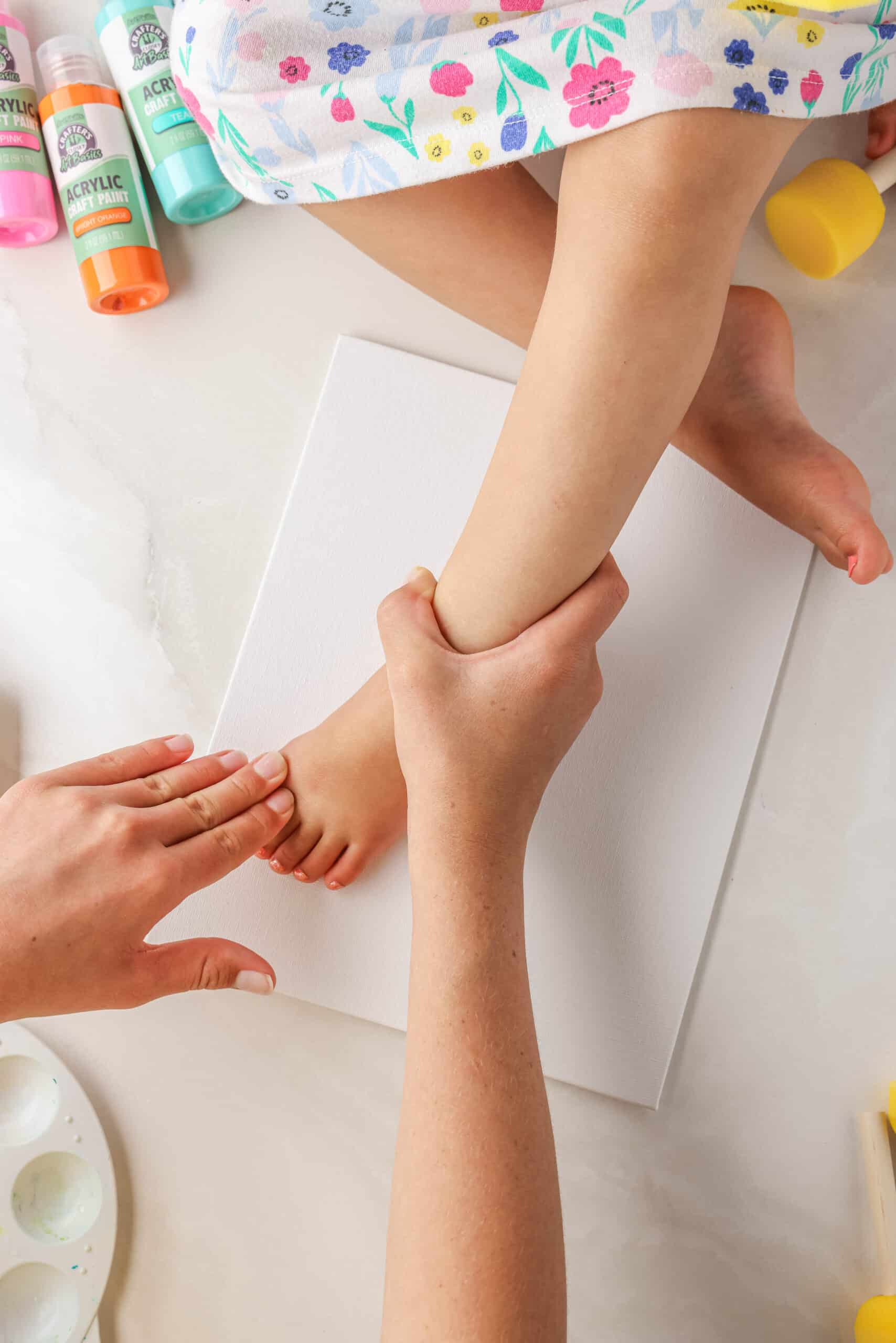 Once the glue is painted nicely on the bottom of the foot guide the childs foot onto the canvas and press down to get glue on the canvas