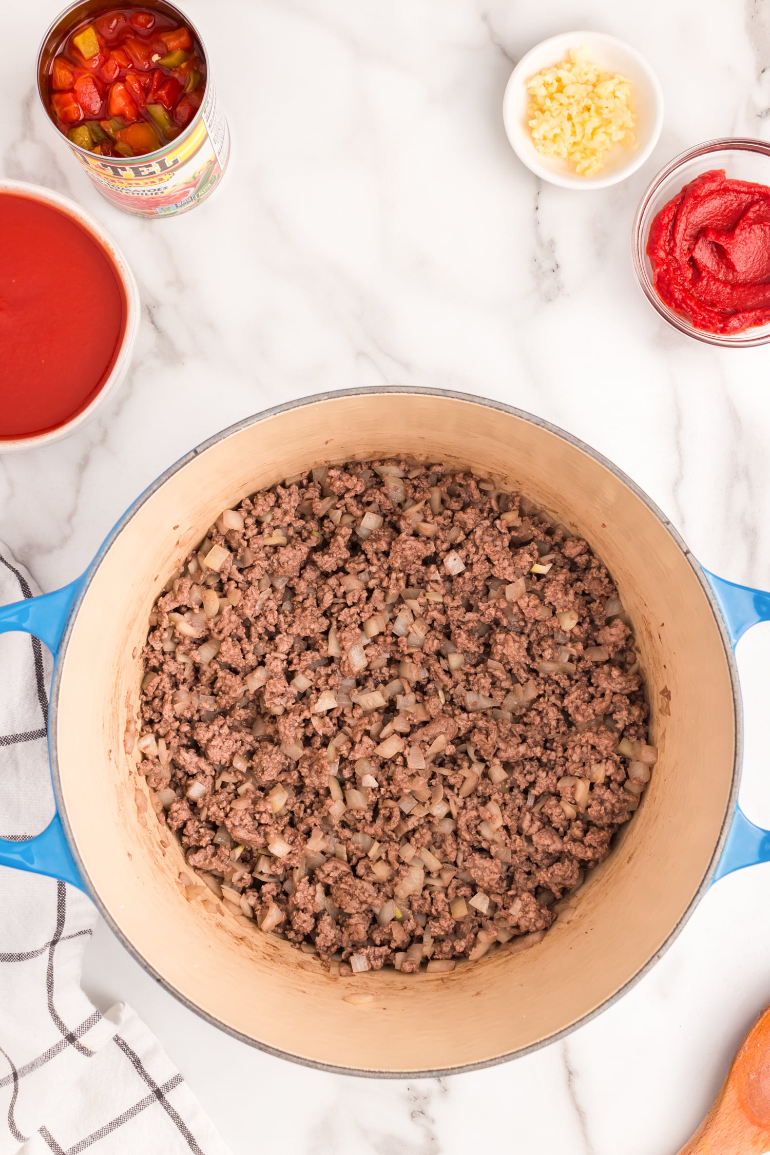 Brown ground beef and onion in a dutch oven. Once brown, add garlic and cook for 1 minute until fragrant.