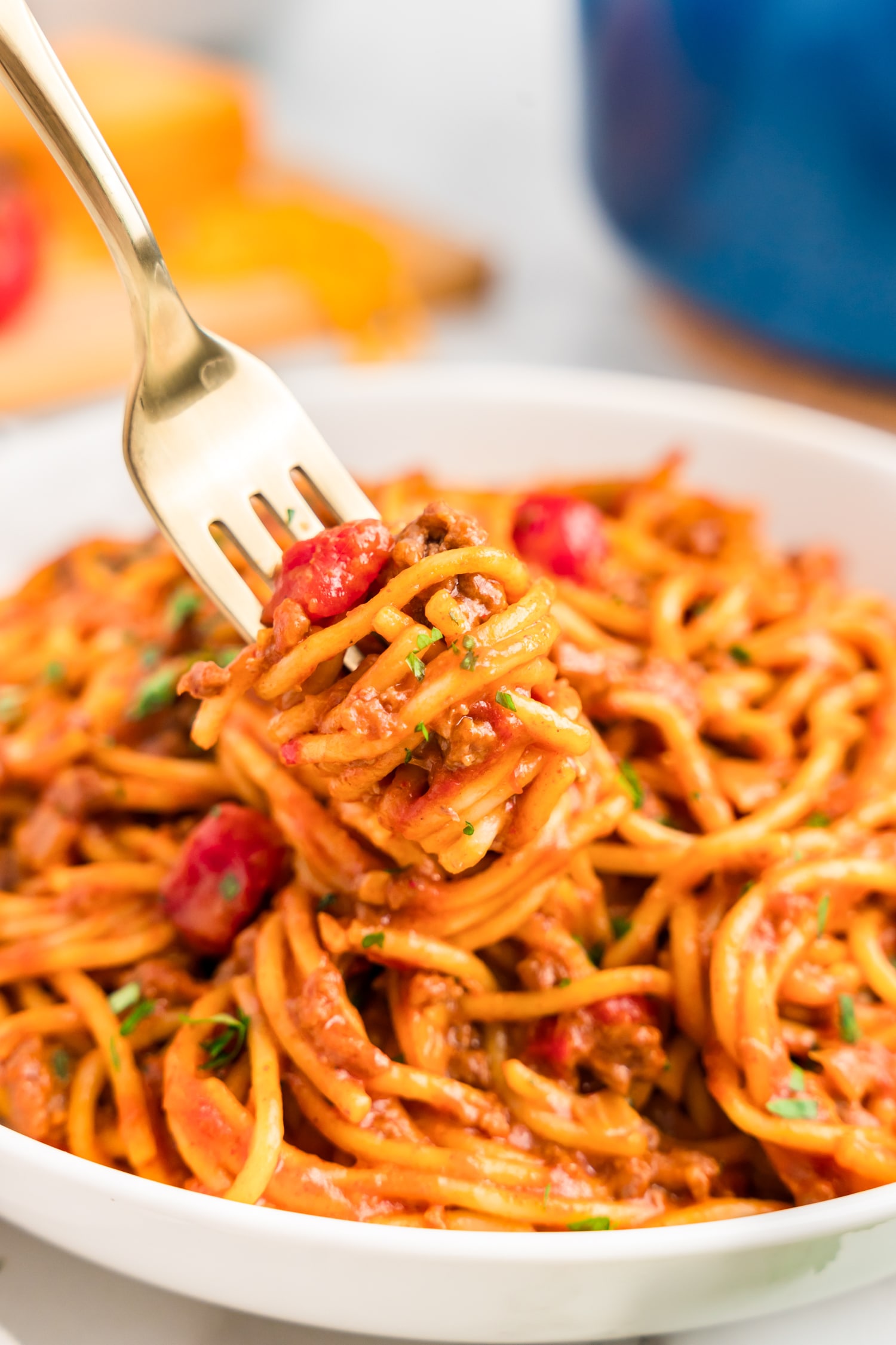 Taco Spaghetti twisted around a fork over a plate full of taco spaghetti.