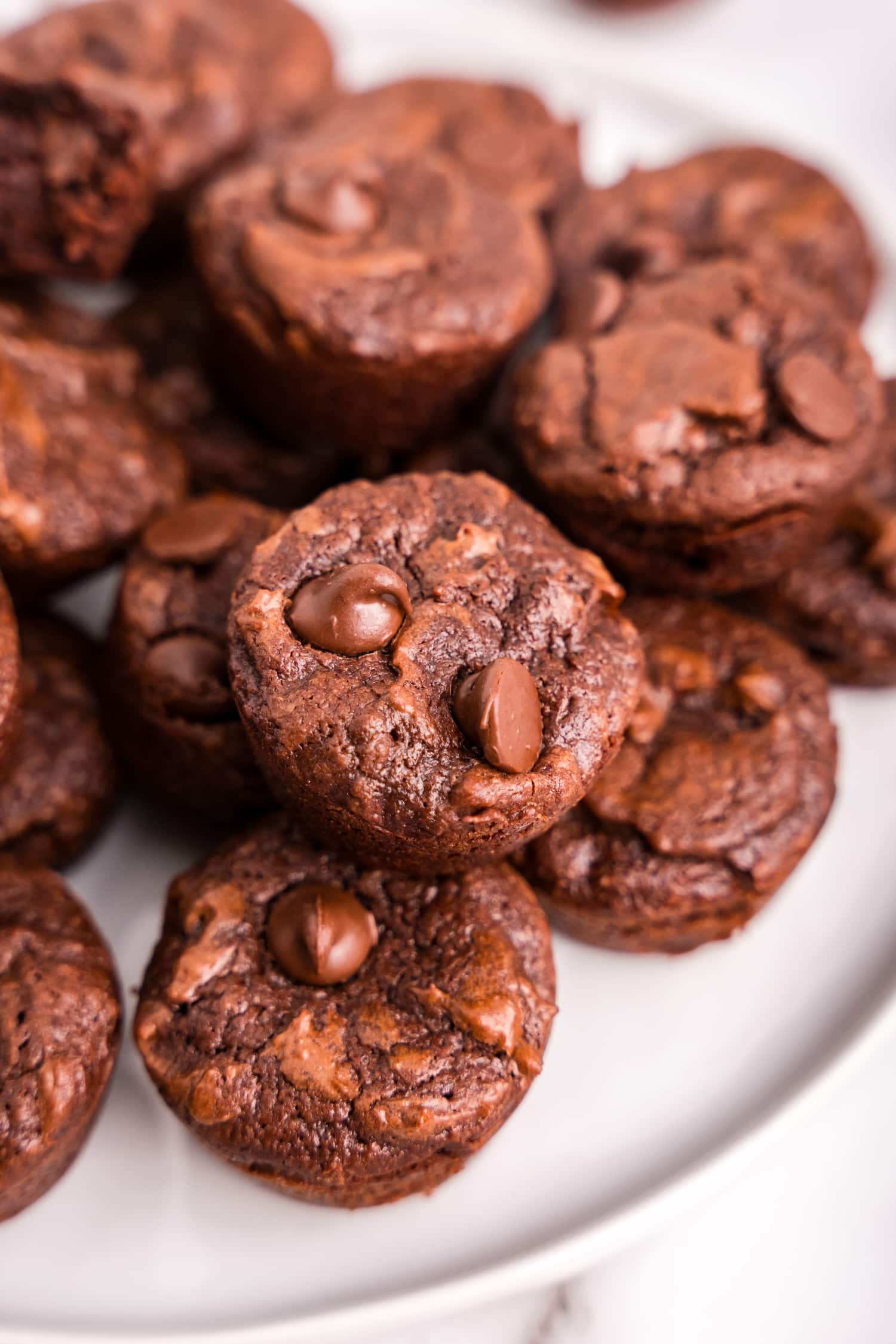 A pile of brownie bites stacked on a white plate.
