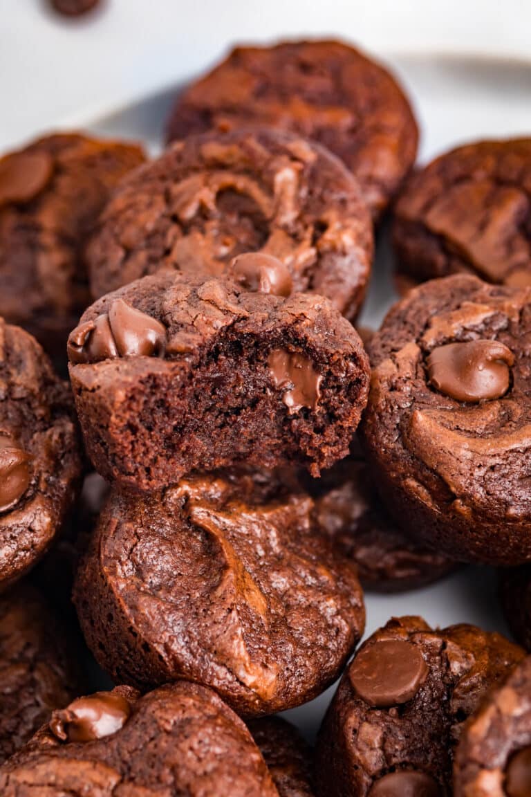 A pile of brownie bites stacked on top of one another with a bite taken out of the top one.