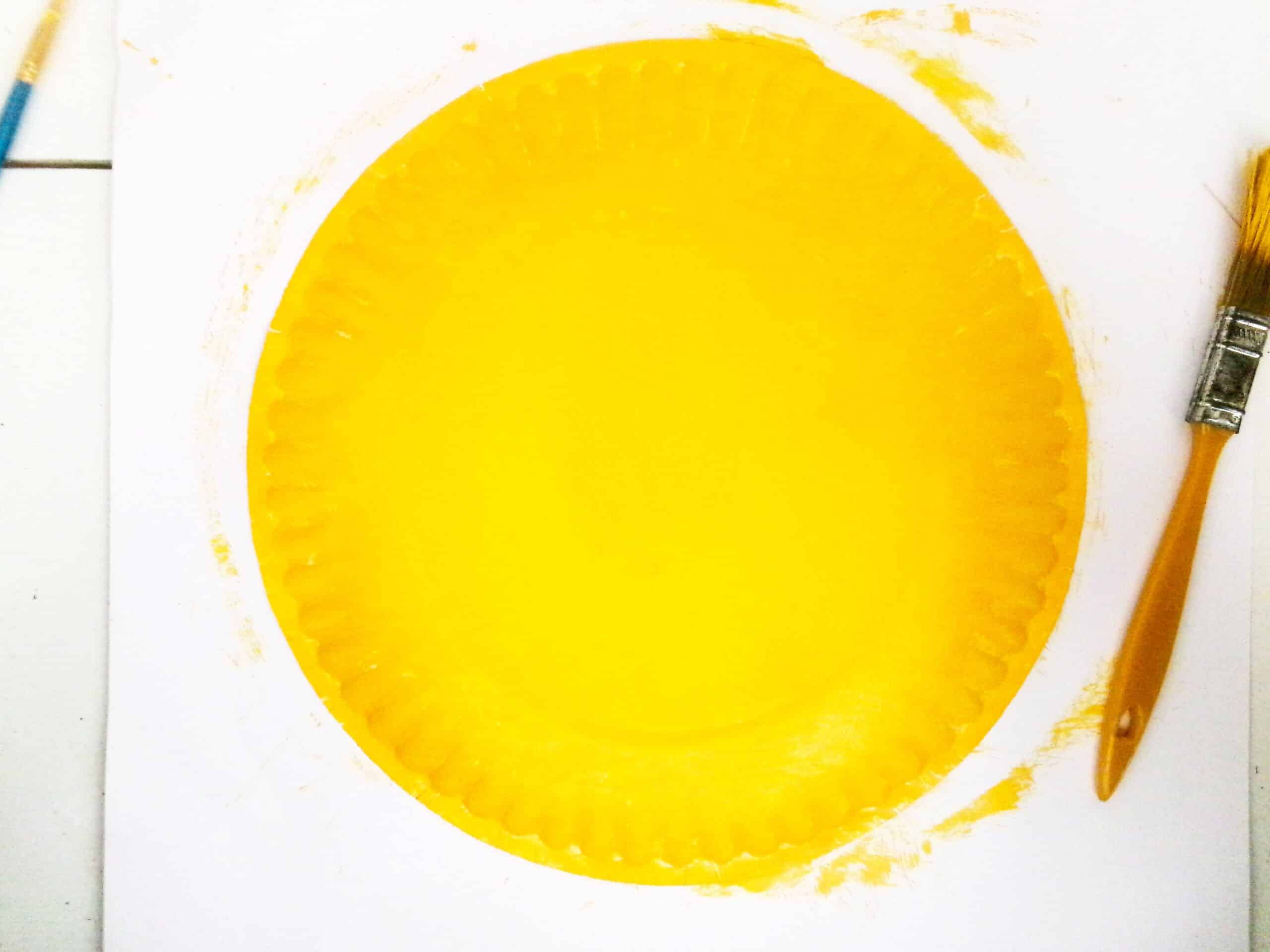 Begin by painting the back of a paper plate yellow.