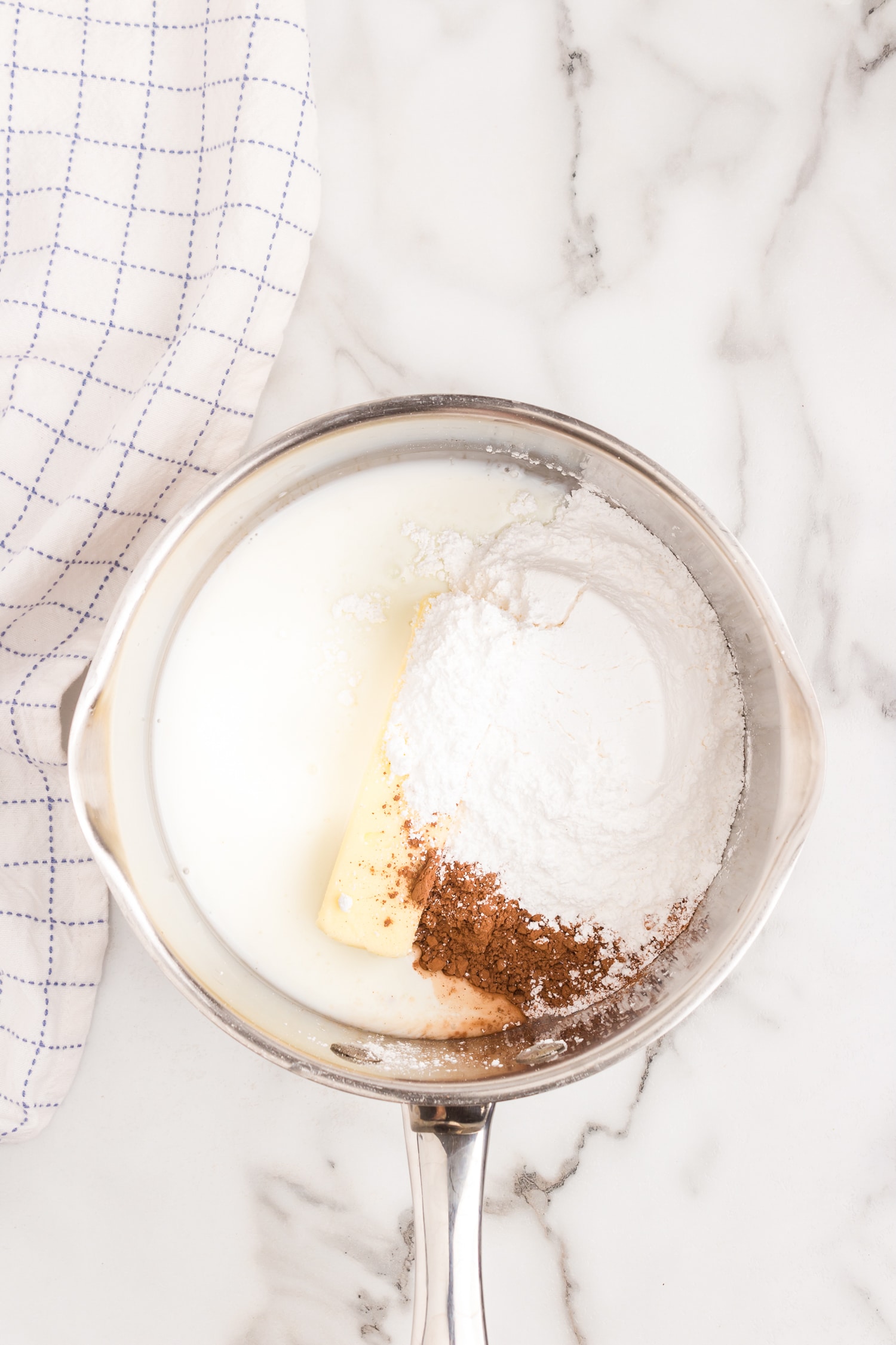 Make the frosting by combining buttermilk, cocoa and butter in a medium saucepan. Bring to a boil and add in powder sugar