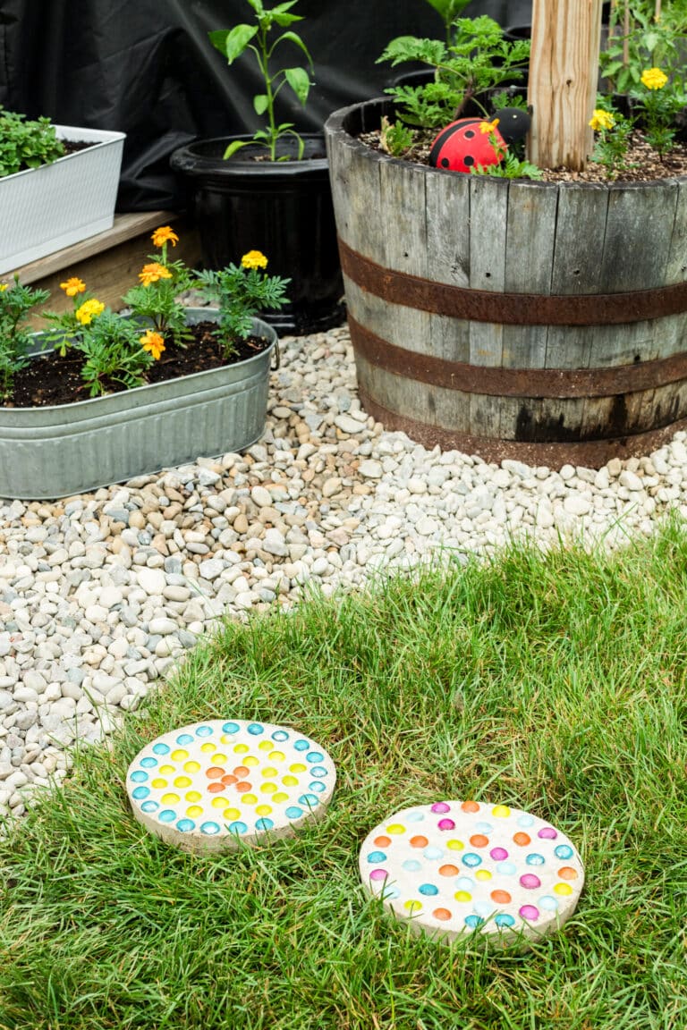 Two completed stepping stones in the grass next to a rock bed with flowers in it.