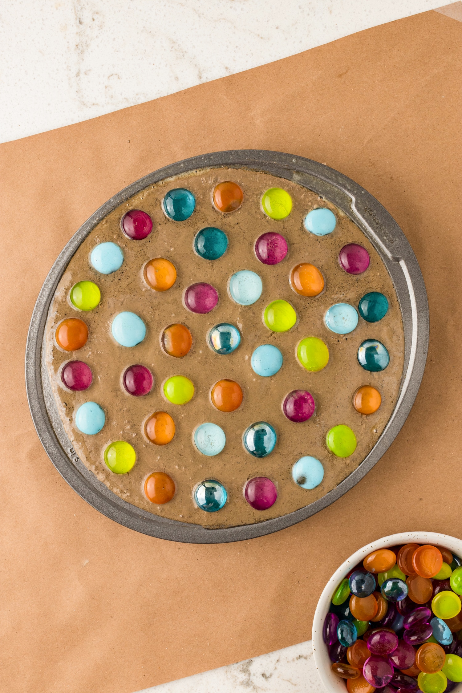 Carefully pour the concrete mix into the cake pan and start adding your stones to the mixture.