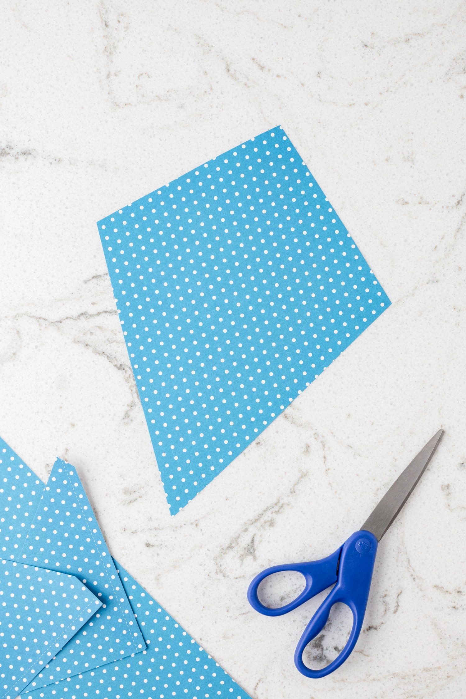 Using a scissor to cut the kite from cardstock for Paper Kite Craft