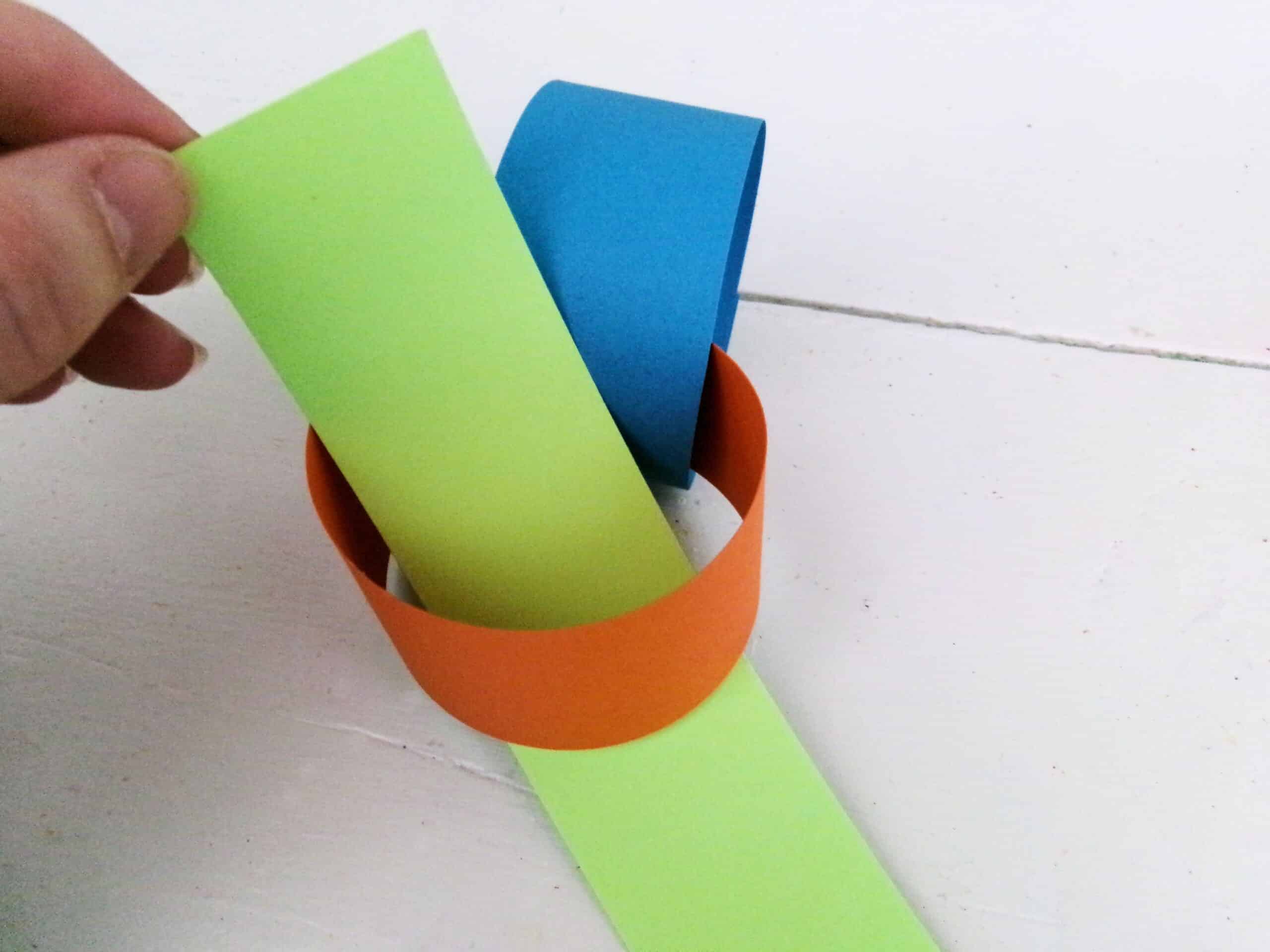 Bring another strip of paper through the loop and staple the ends together.
