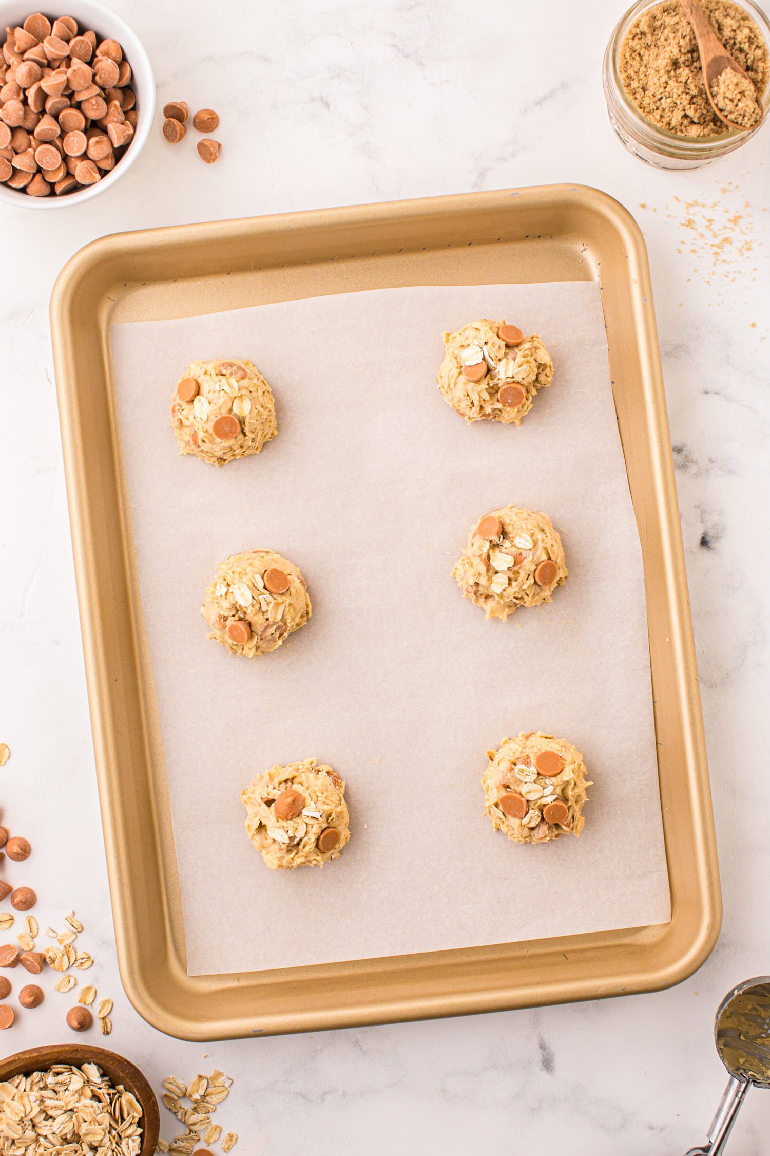 Using a 1 1/2 tablespoon cookie scoop to drop cookies onto a prepared cookie sheet.