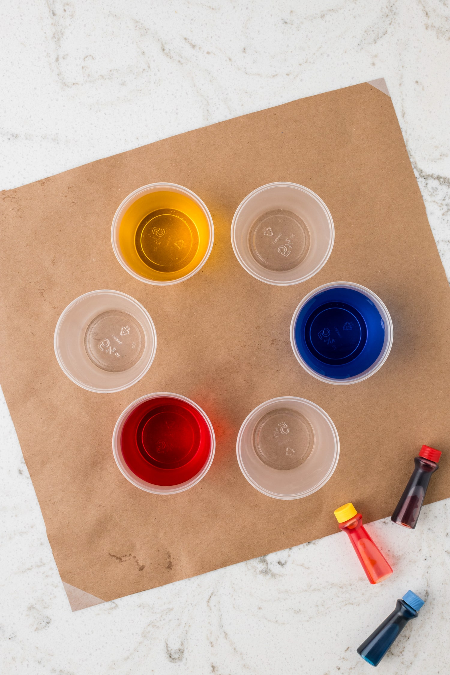 Fill every other cup half way with water & add a few drops of food coloring into the water.
