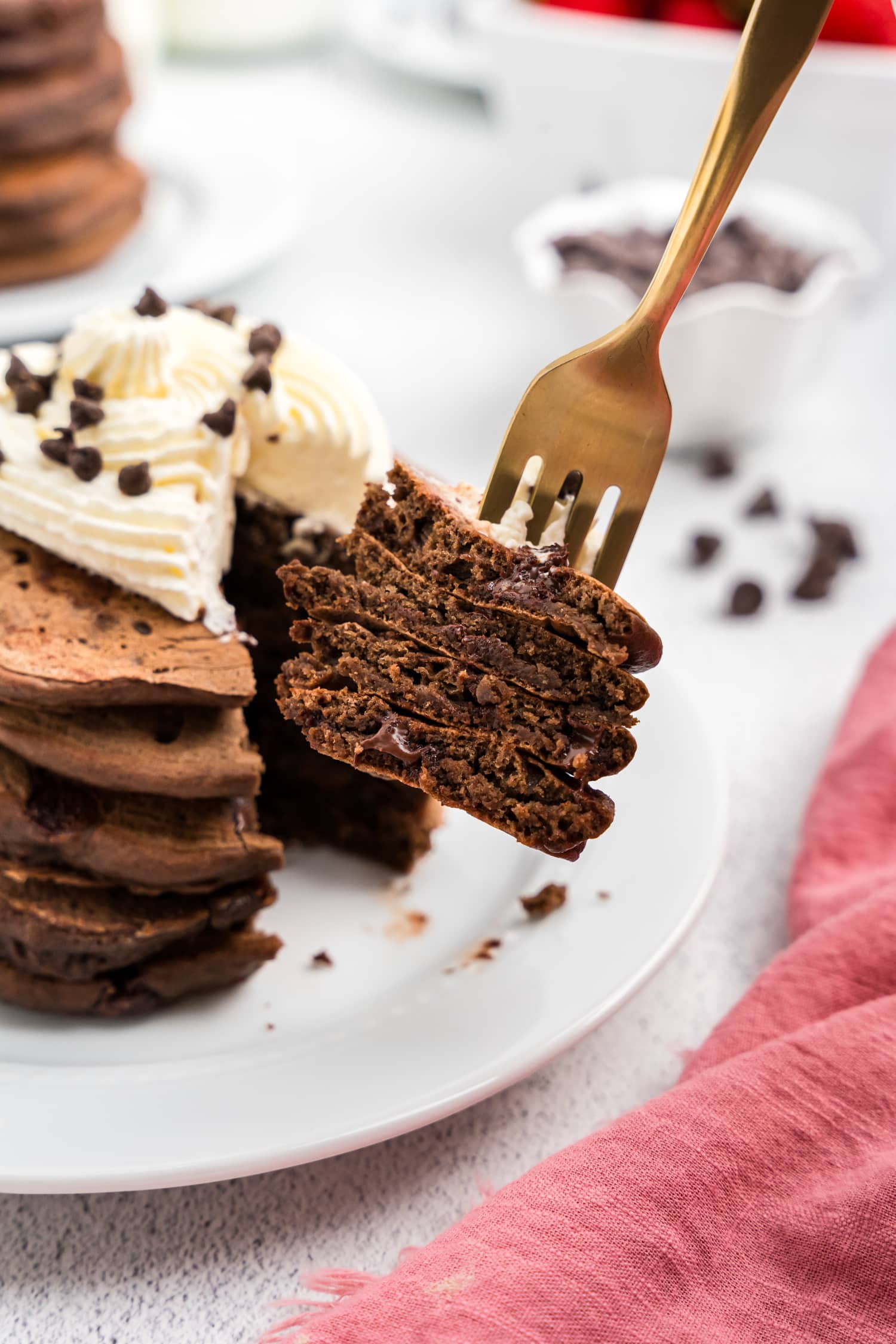 Fork with a stack of chocolate pancakes on it.