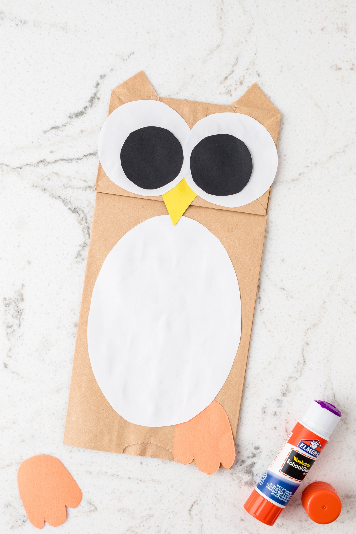 Using a glue stick to add orange feet on the Paper Bag Owl Craft