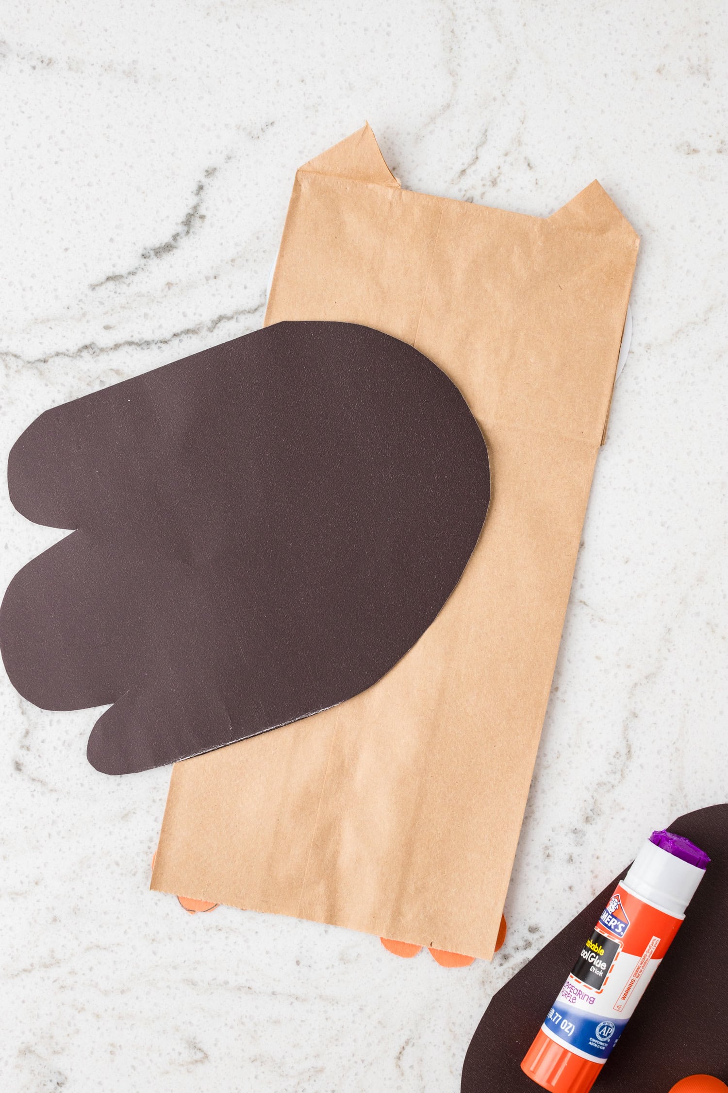 After flipping brown paper bag over, use a glue stick to affix large brown wings to the Paper Bag Owl Craft