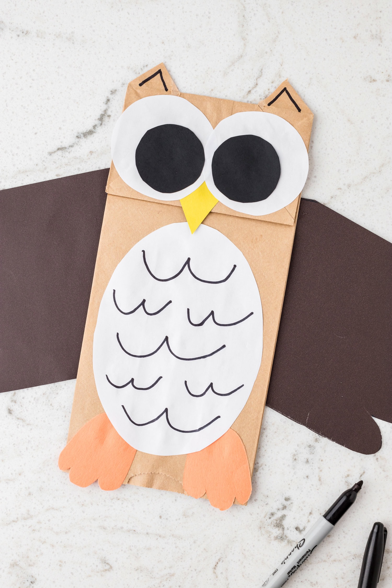 Using a black marker to add details to the owl's oval white belly for the Paper Bag Owl Craft