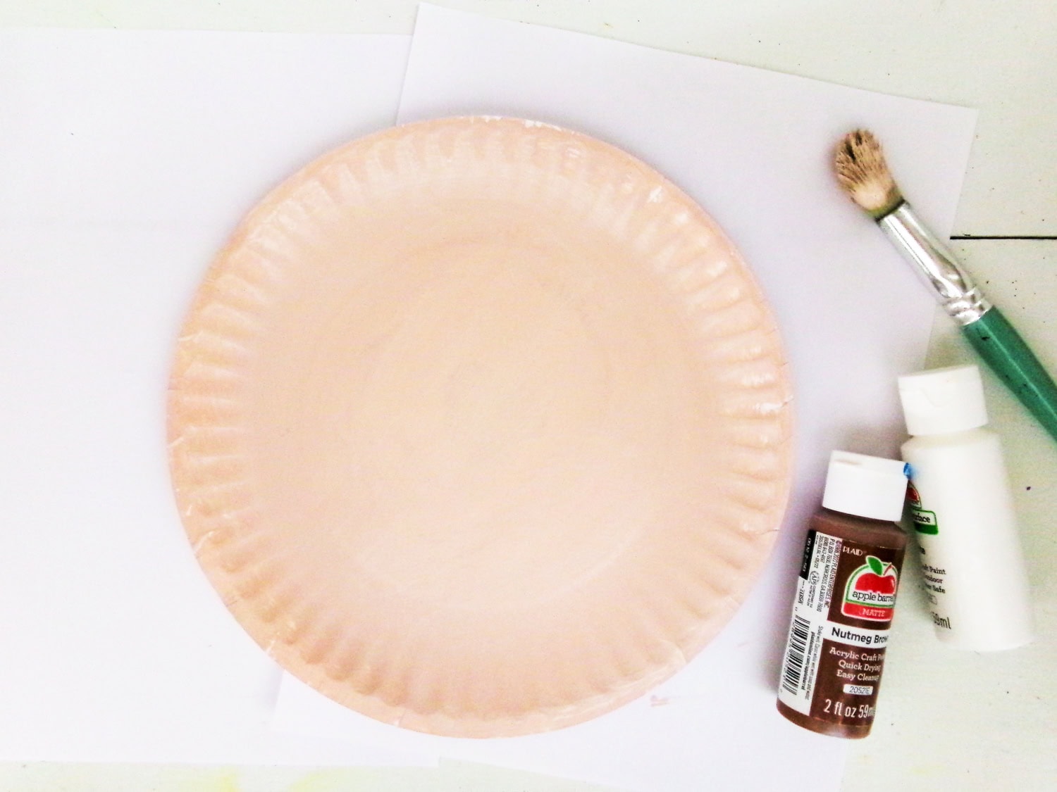 Mixing brown and white paint to form tan for the Paper Plate Scarecrow Craft face that is painted on paper plate