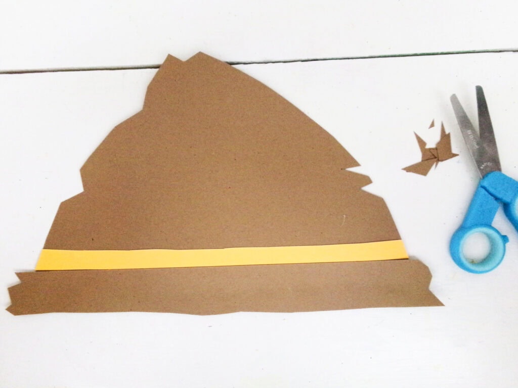 Using a scissor to cut jagged edges of the hat for a worn look for the Paper Plate Scarecrow Craft