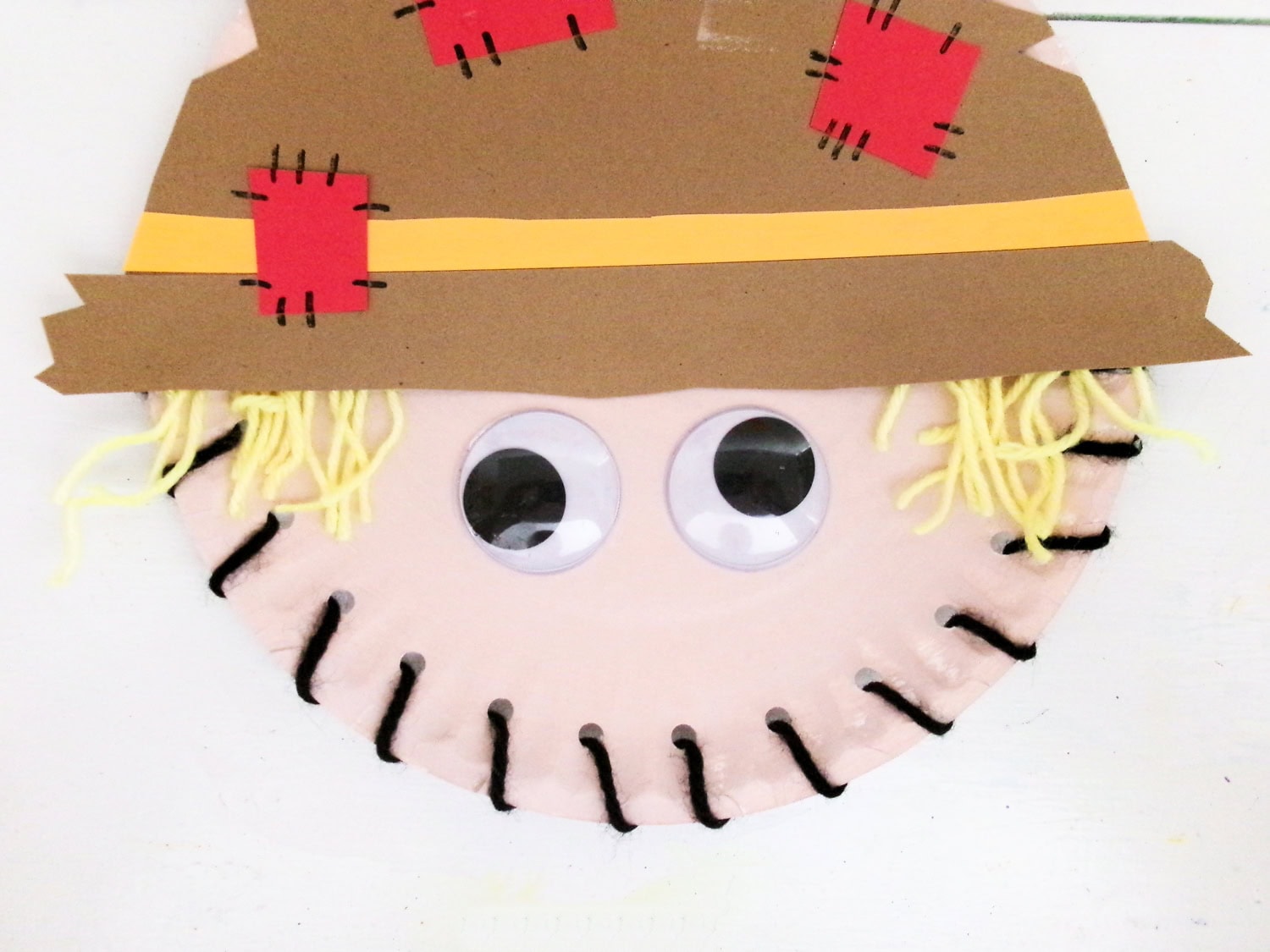 Gluing the googly eyes to the scarecrow face for the Paper Plate Scarecrow Craft