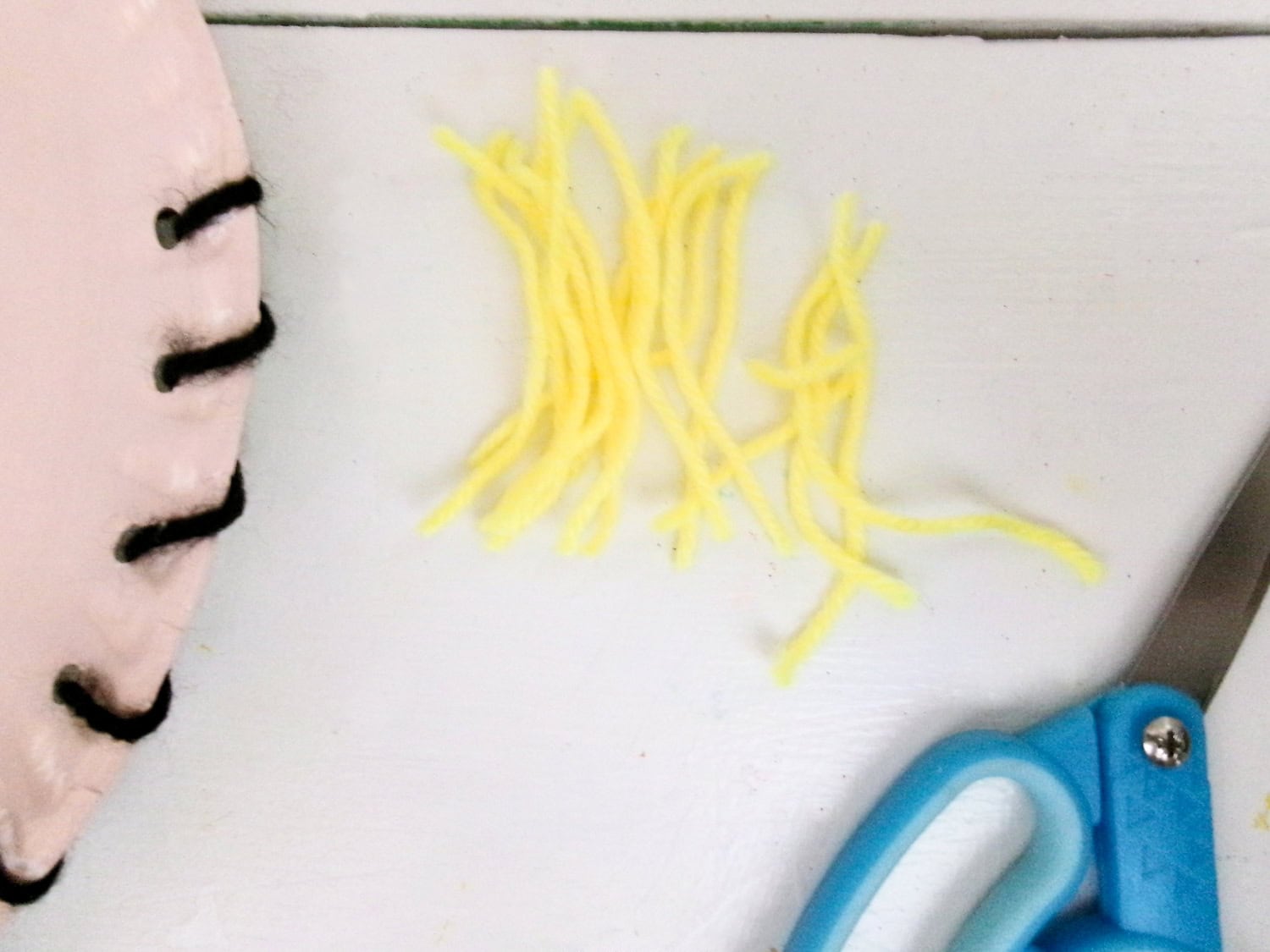 Cutting small pieces of yellow yard for the Paper Plate Scarecrow Craft straw hair