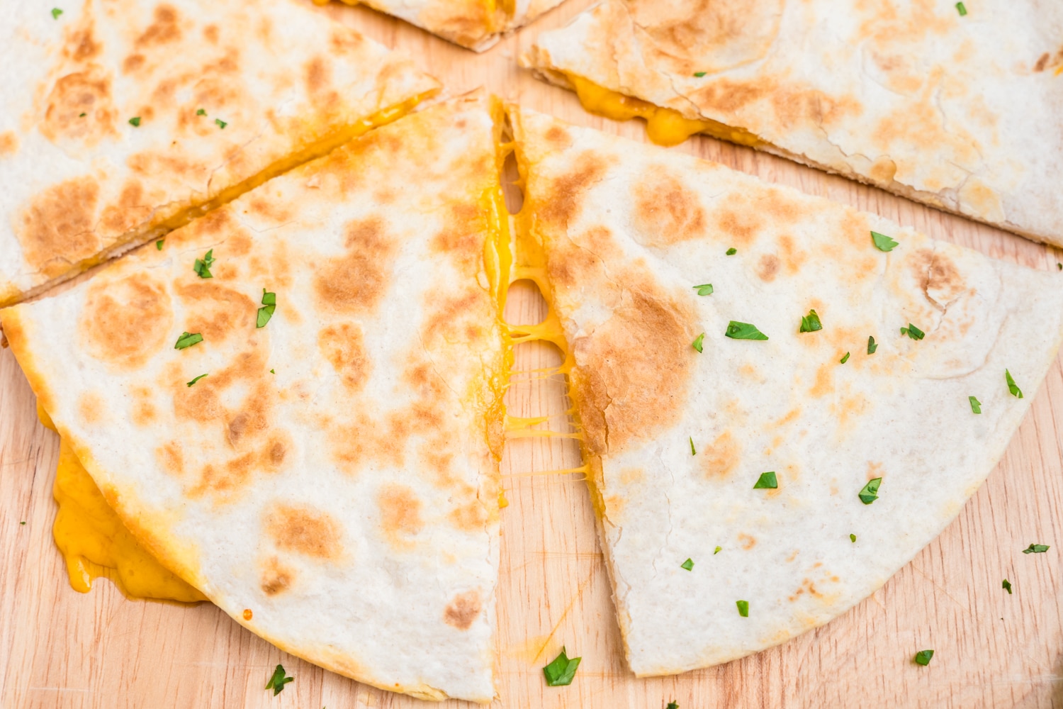 Cheese Quesadilla cut into triangles on wooden cutting board