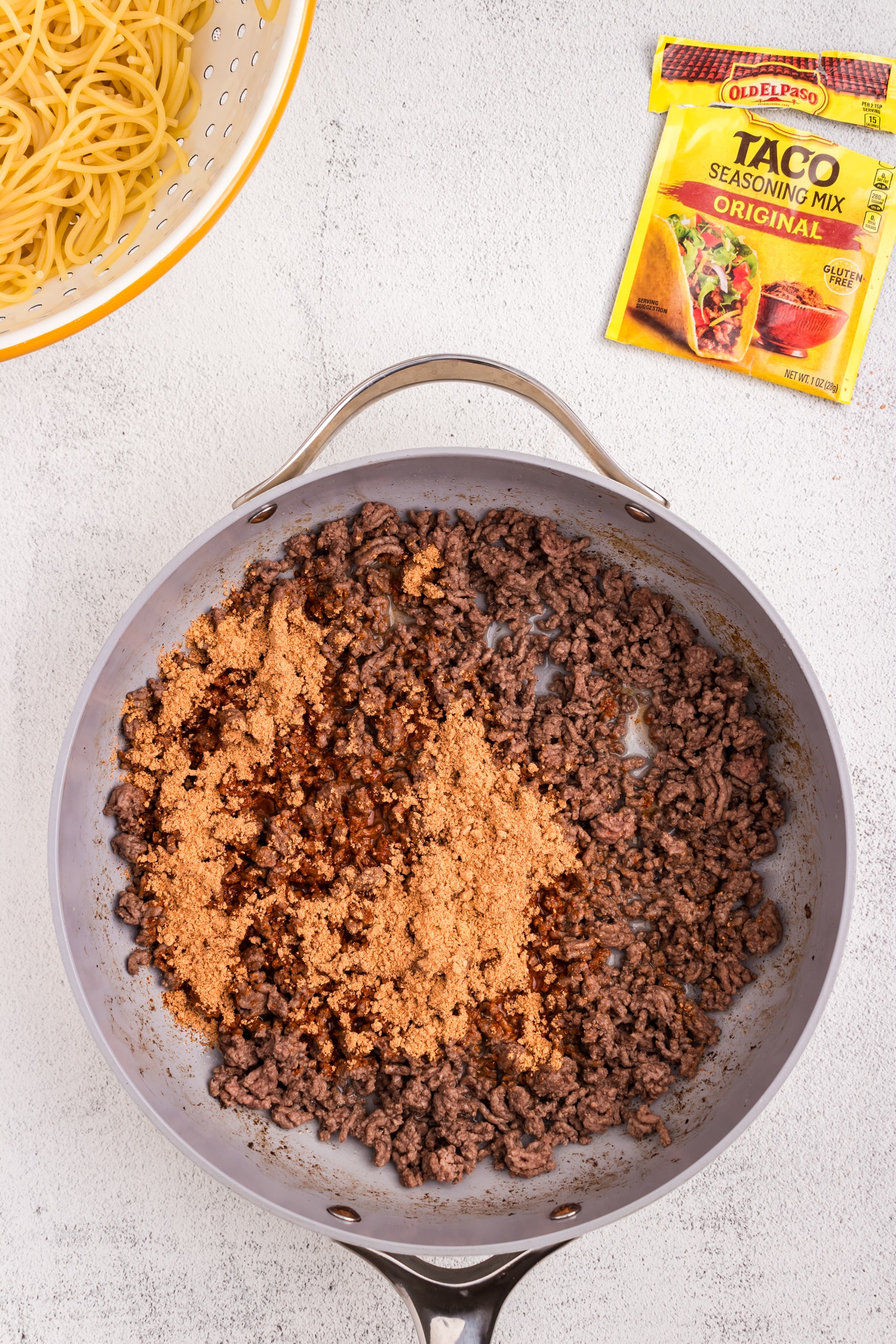 Browning ground beef and taco seasoning in stovetop skillet for Spaghetti Tacos