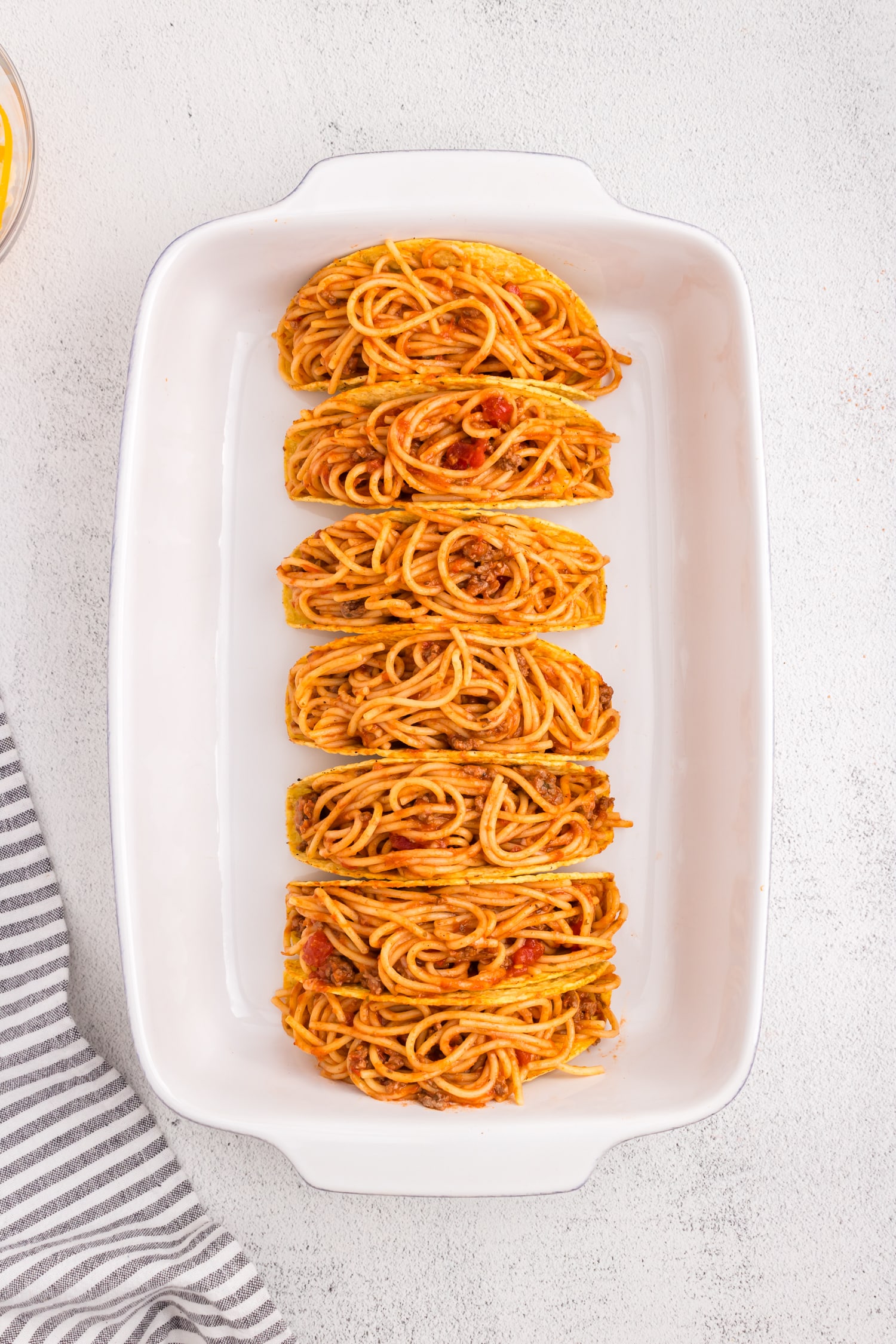 Filling tfree standing taco shells with Spaghetti Tacos mixture in 9x13 baking pan