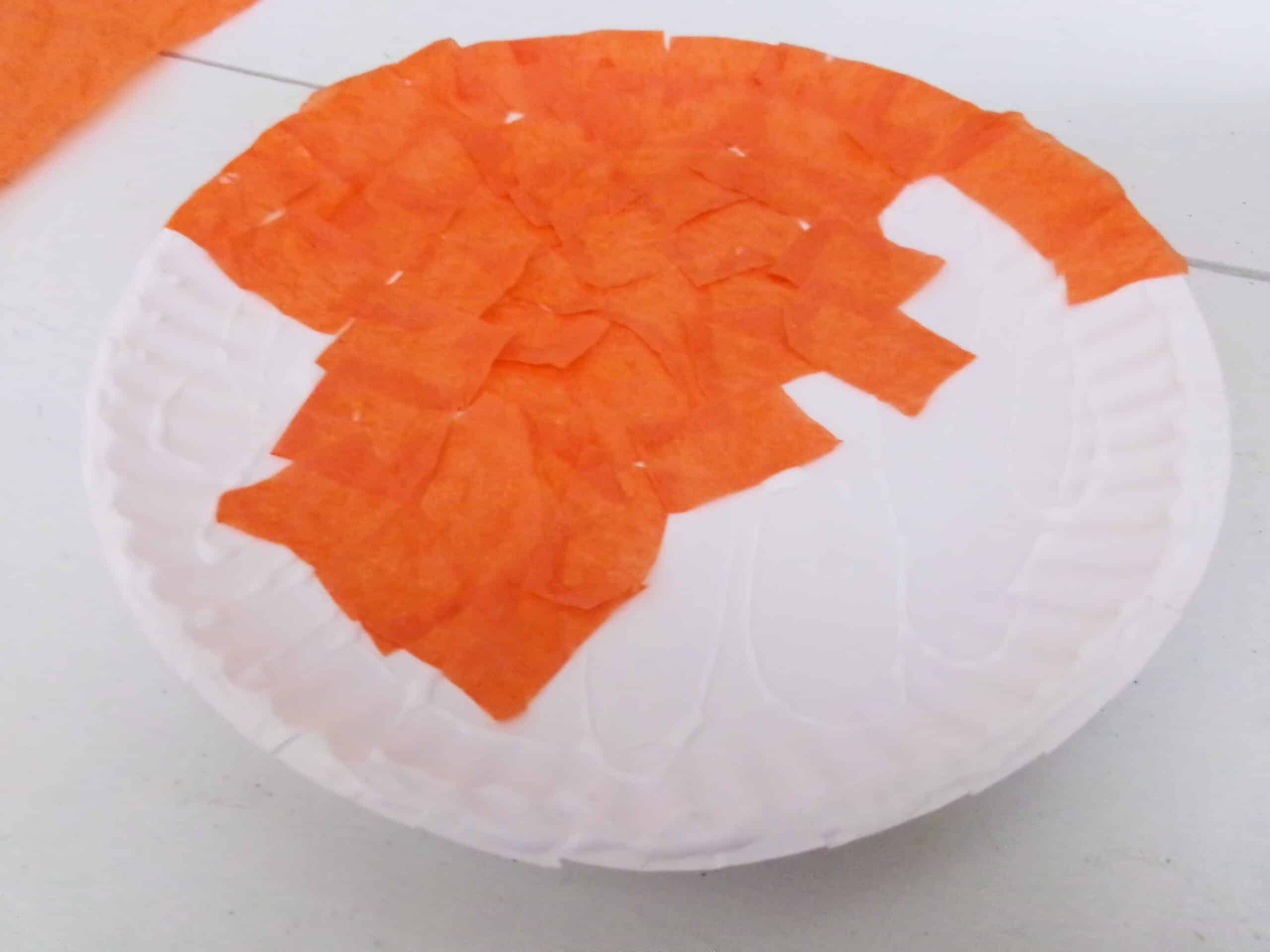 Keep adding tissue paper until the whole paper plate is covered.