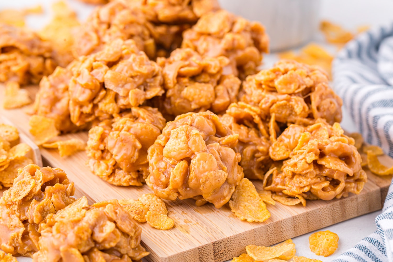 Photo of Cornflake Cookies in a pile on top of a wooden cutting board.