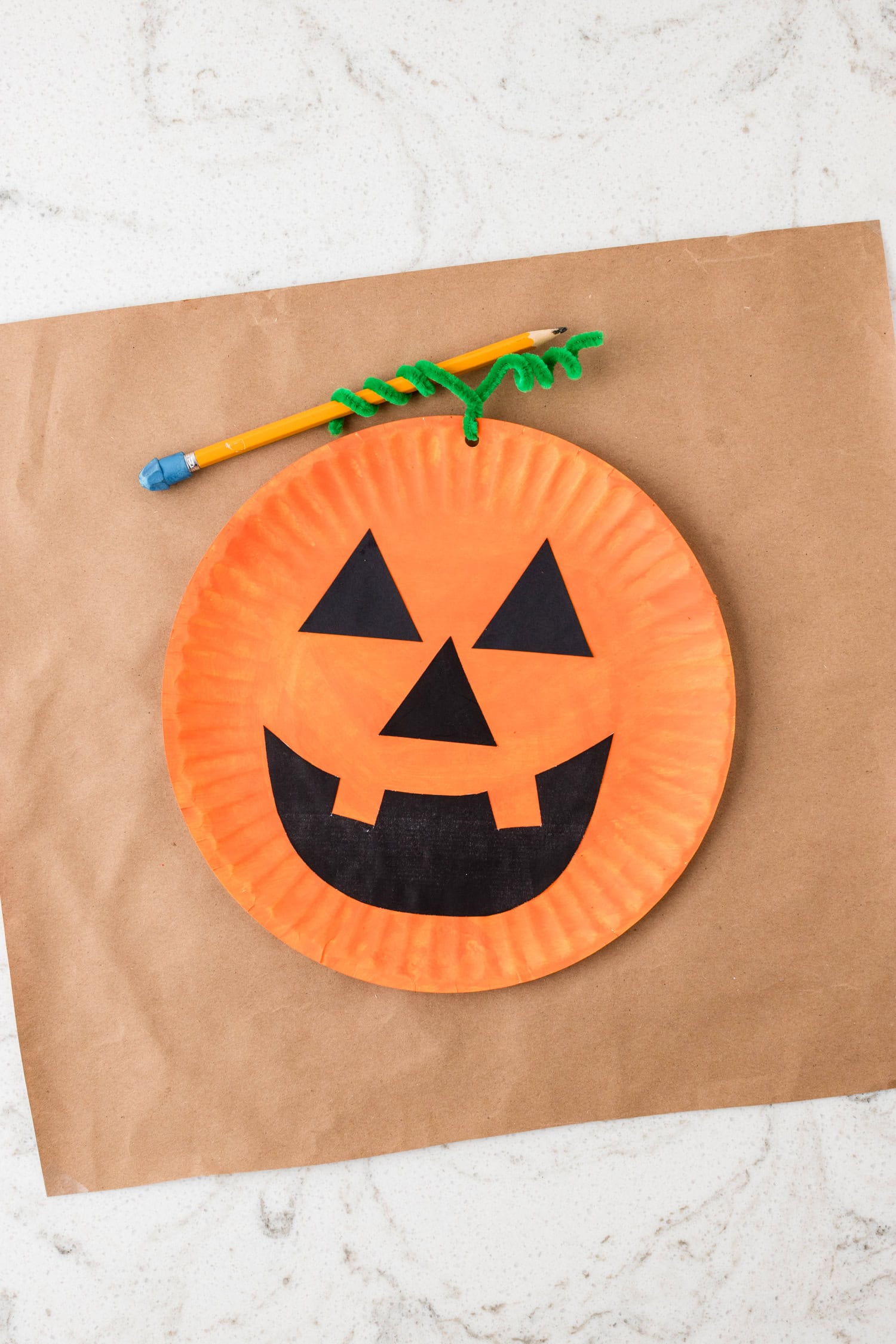 Wrapping the green pipe cleaner around a pencil to give it a vine look for the Paper Plate Pumpkin Craft
