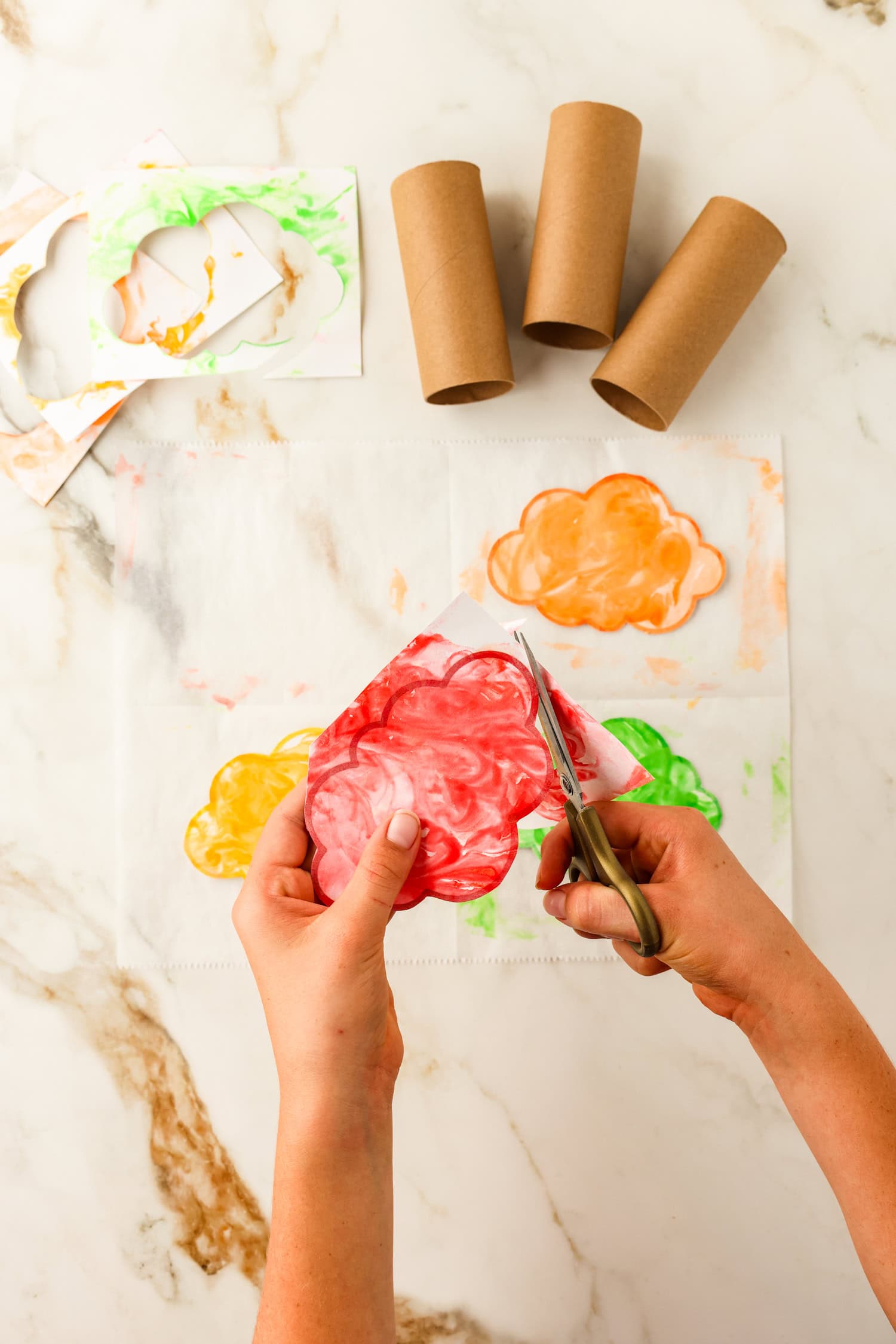 Cutting around the cloud outline after pressing into colored shaving cream for Toilet Paper Roll Fall Tree Craft