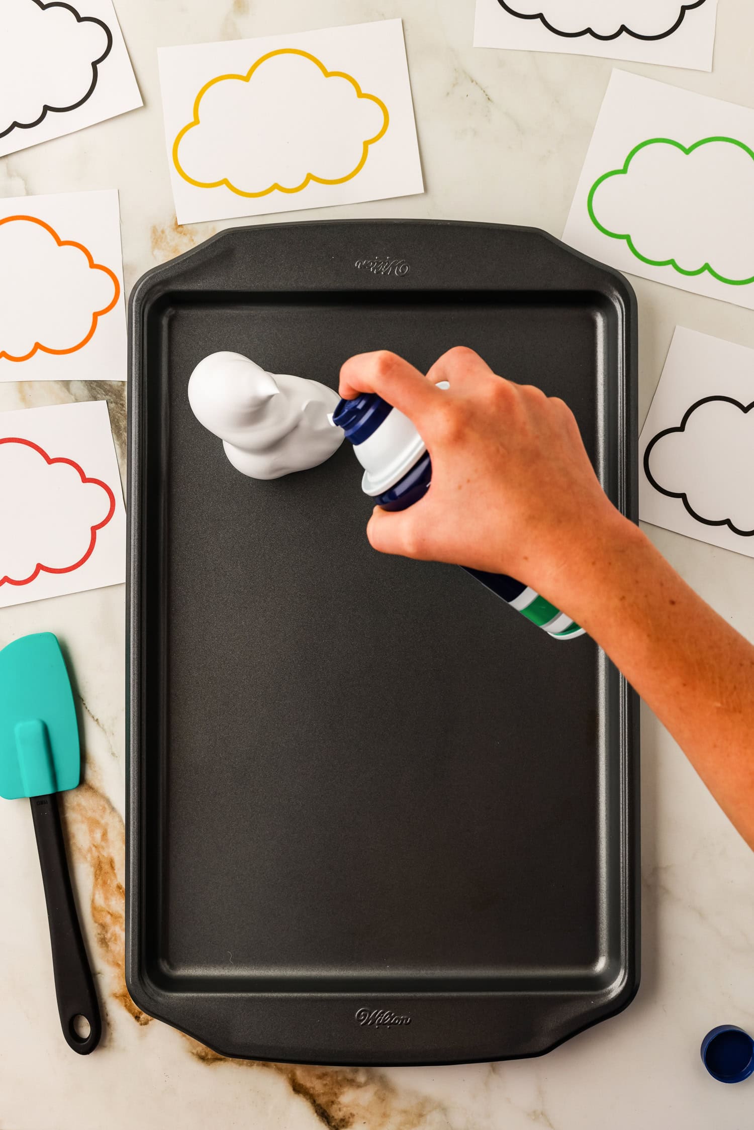 Creating cloud shapes on a sheet pan with shaving cream for the Toilet Paper Roll Fall Tree Craft