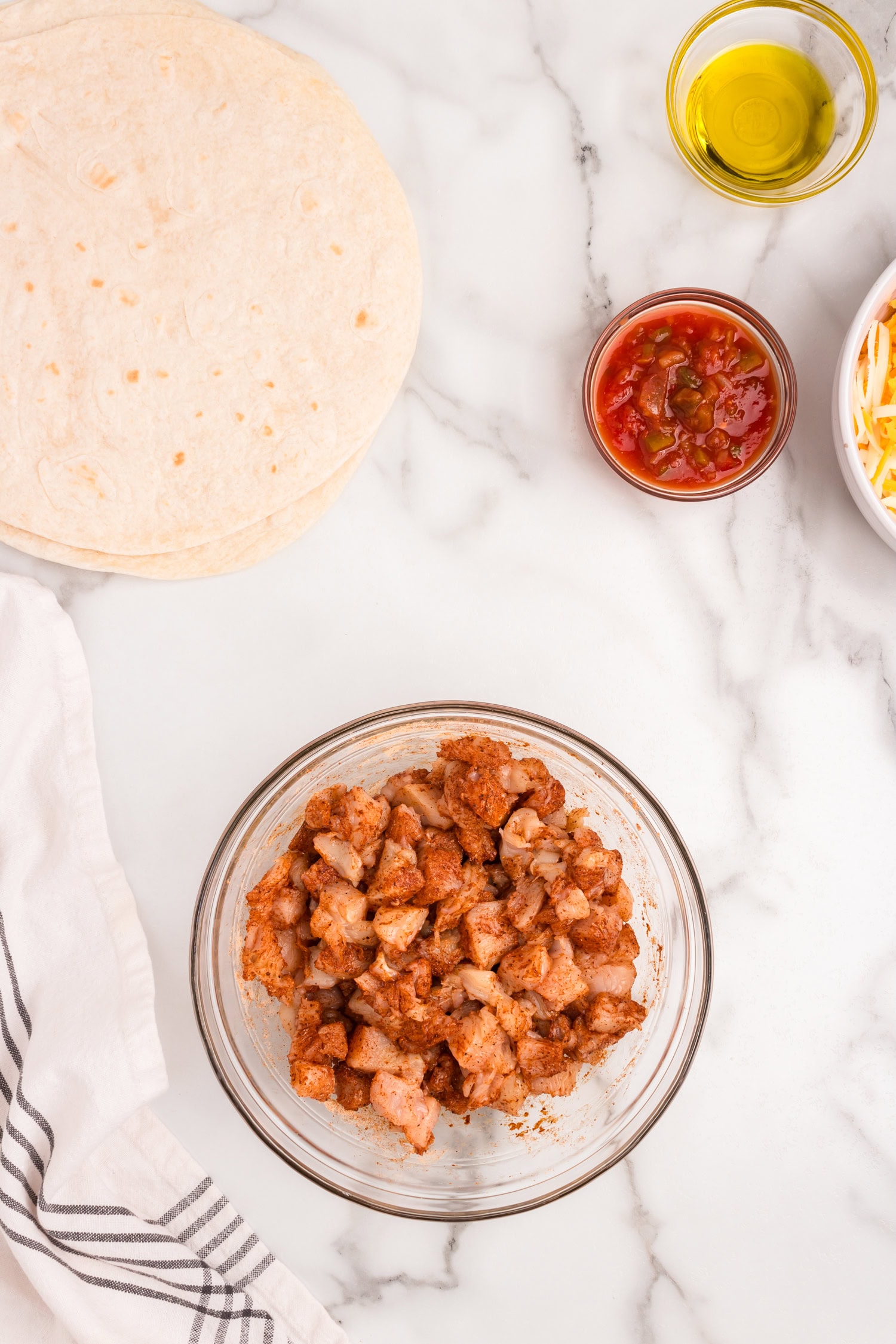 Cubed chicken coated in taco seasoning in small mixing bowl for Chicken Quesadilla recipe