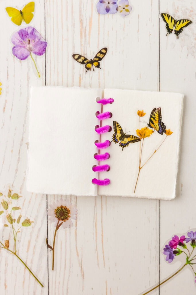 Adding stickers to make a floral and butterfly scene in the DIY Sticker Book
